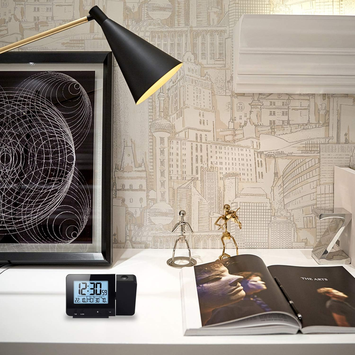 Uhr mit Projektionsanzeige auf einem Schreibtisch. Eine Lampe und Kunst sind im Hintergrund.