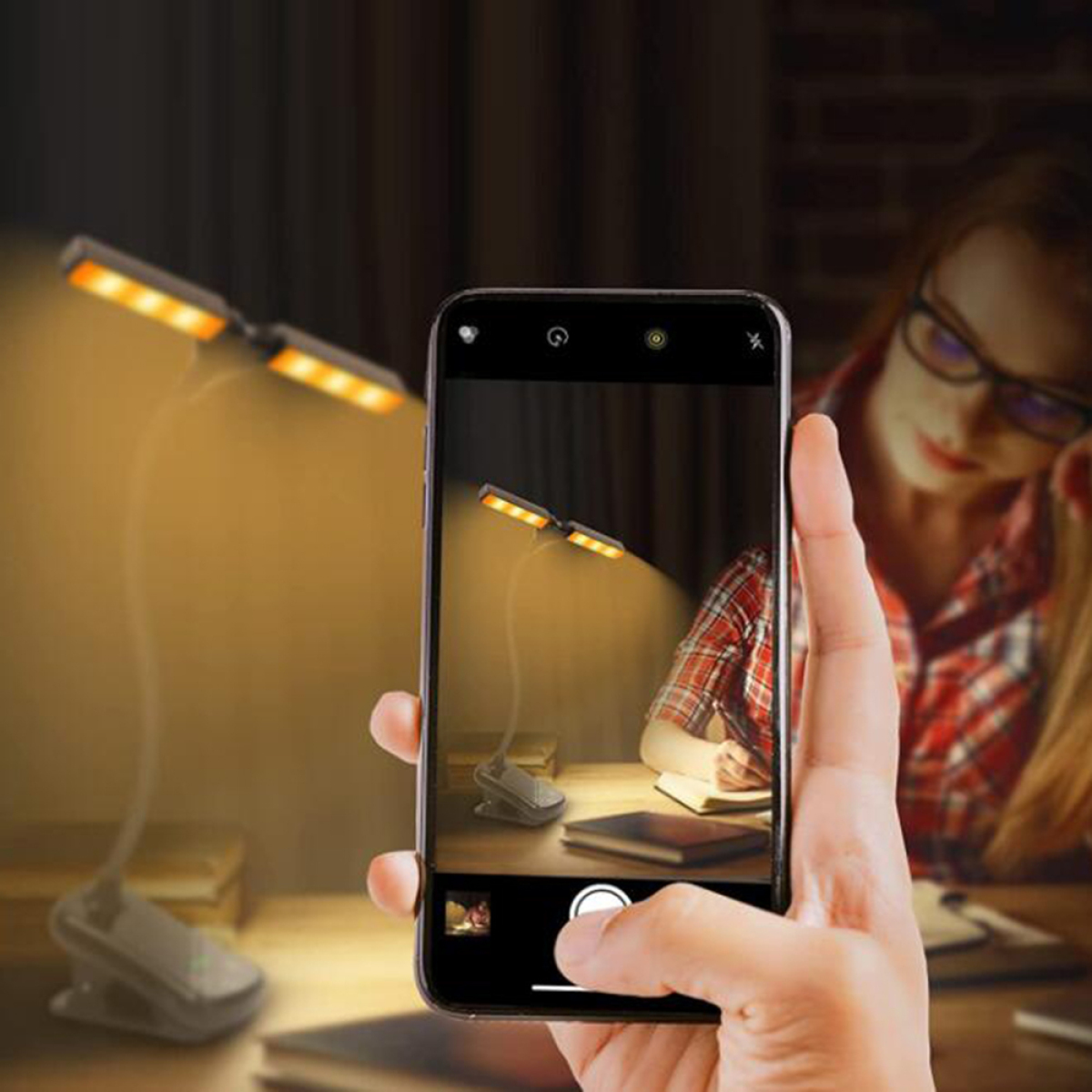 Person macht Foto einer Schreibtischlampe mit Telefon; Frau mit Brille im Hintergrund.