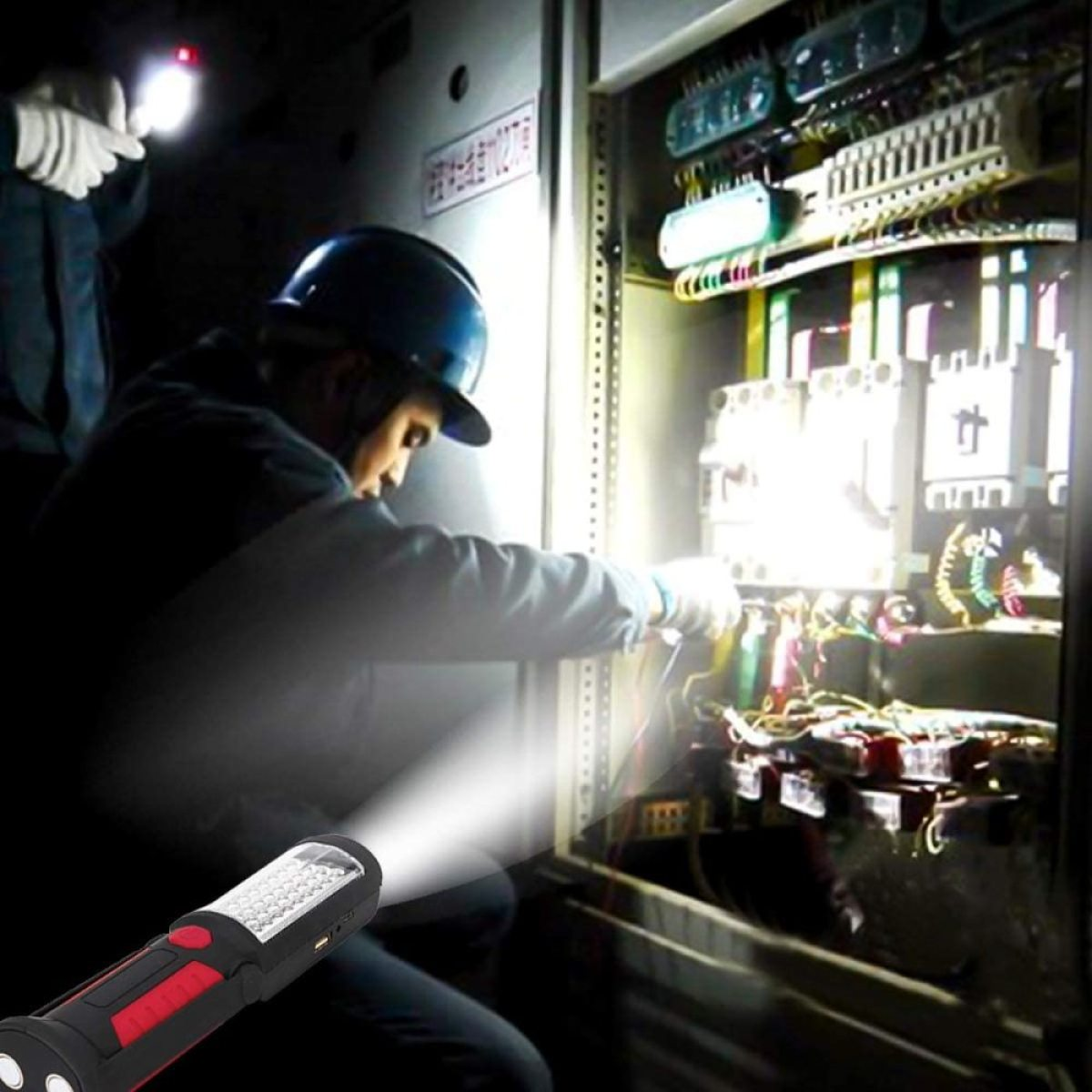 Elektriker, der mit einer Taschenlampe an elektrischen Geräten arbeitet. Eine andere Person ist im Hintergrund.