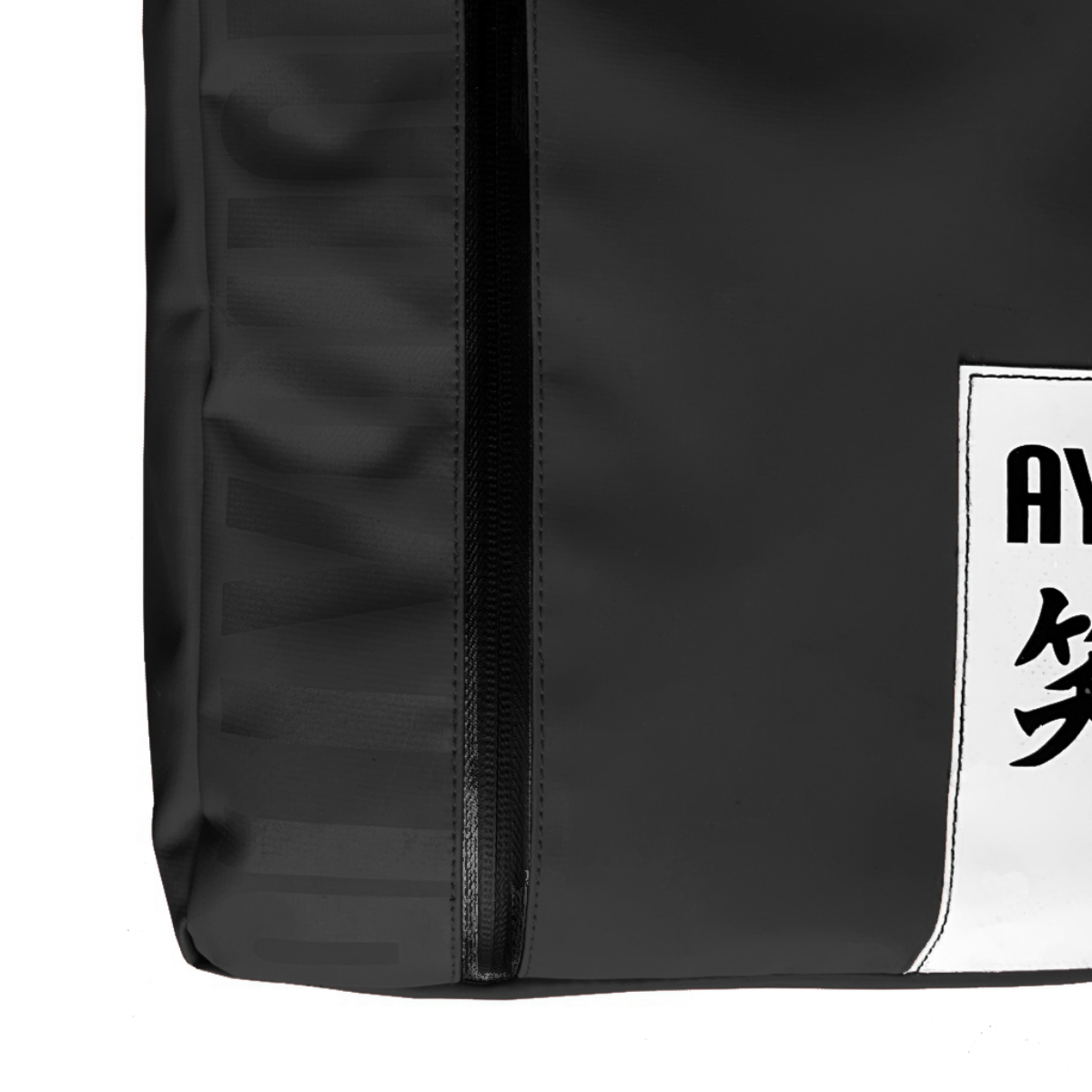 Se muestra una esquina de una bolsa negra con cremallera y una etiqueta blanca con caracteres asiáticos.