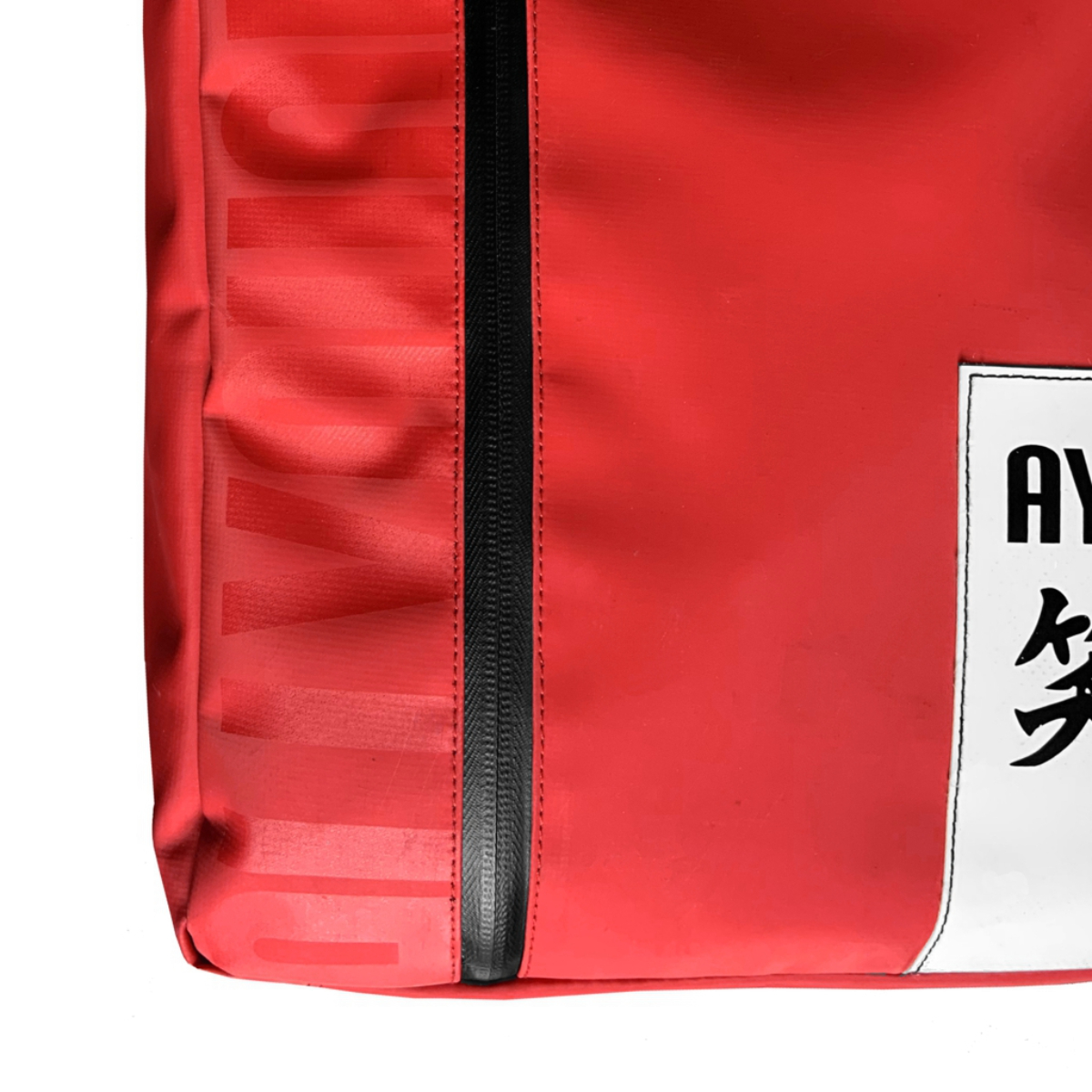 Bolsa roja con cremallera negra y etiqueta blanca con caracteres asiáticos.