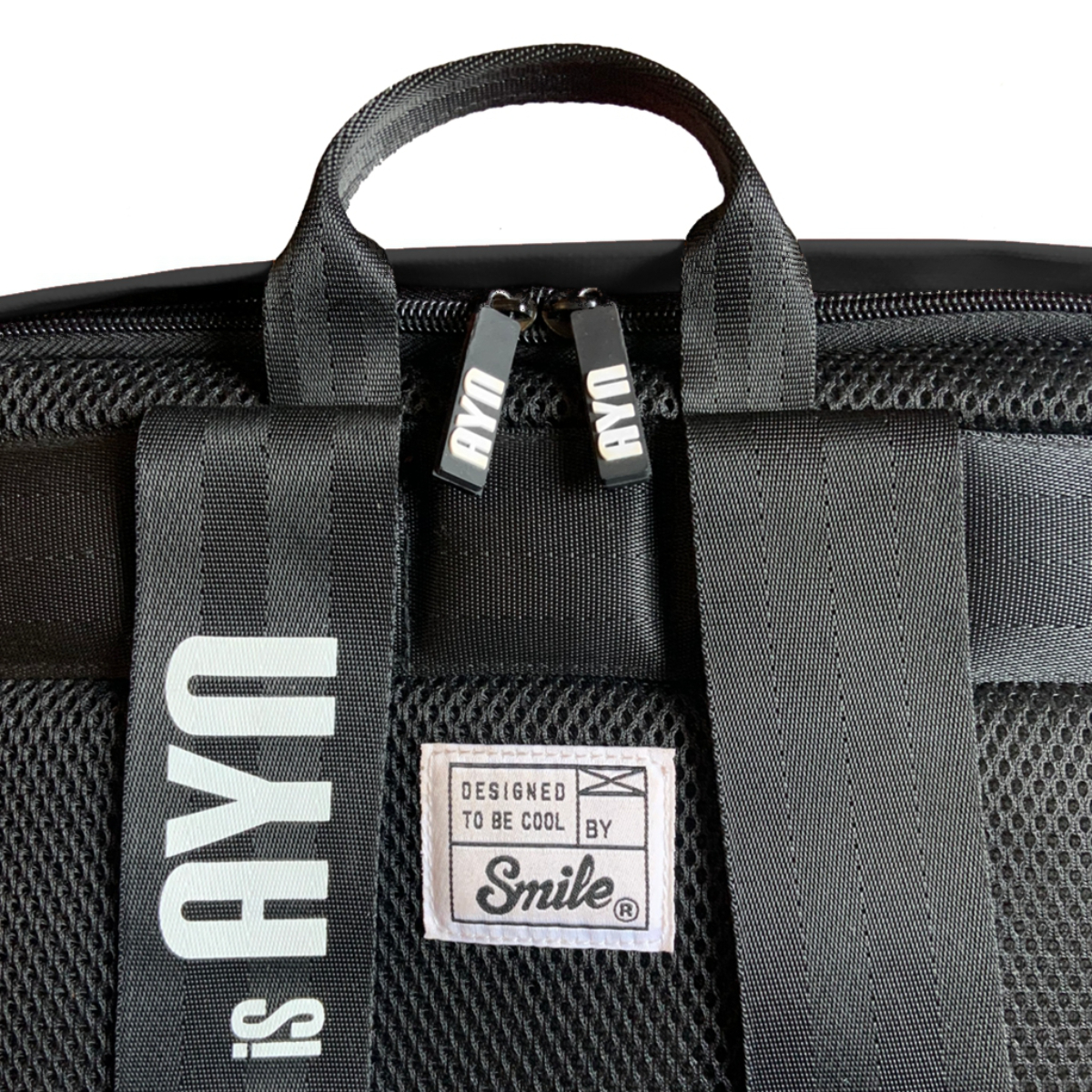 Una mochila negra con el texto blanco "AYN" en la correa y una etiqueta que dice "DESIGNED TO BE COOL BY Smile".