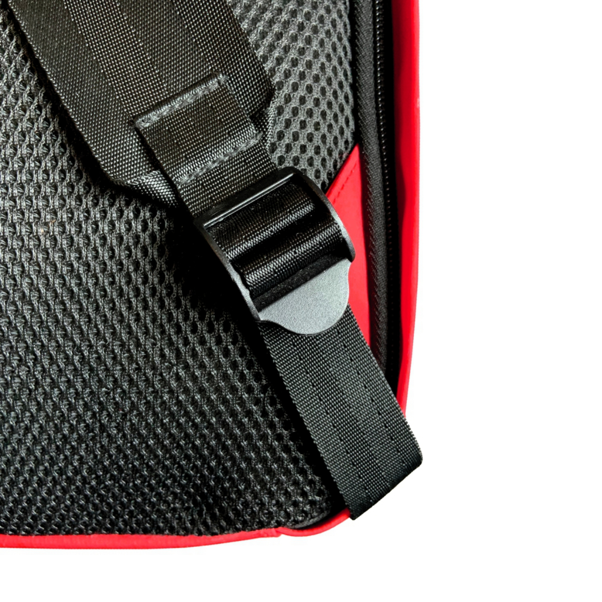 Primer plano de correa de mochila negra y roja con hebilla y material de malla.