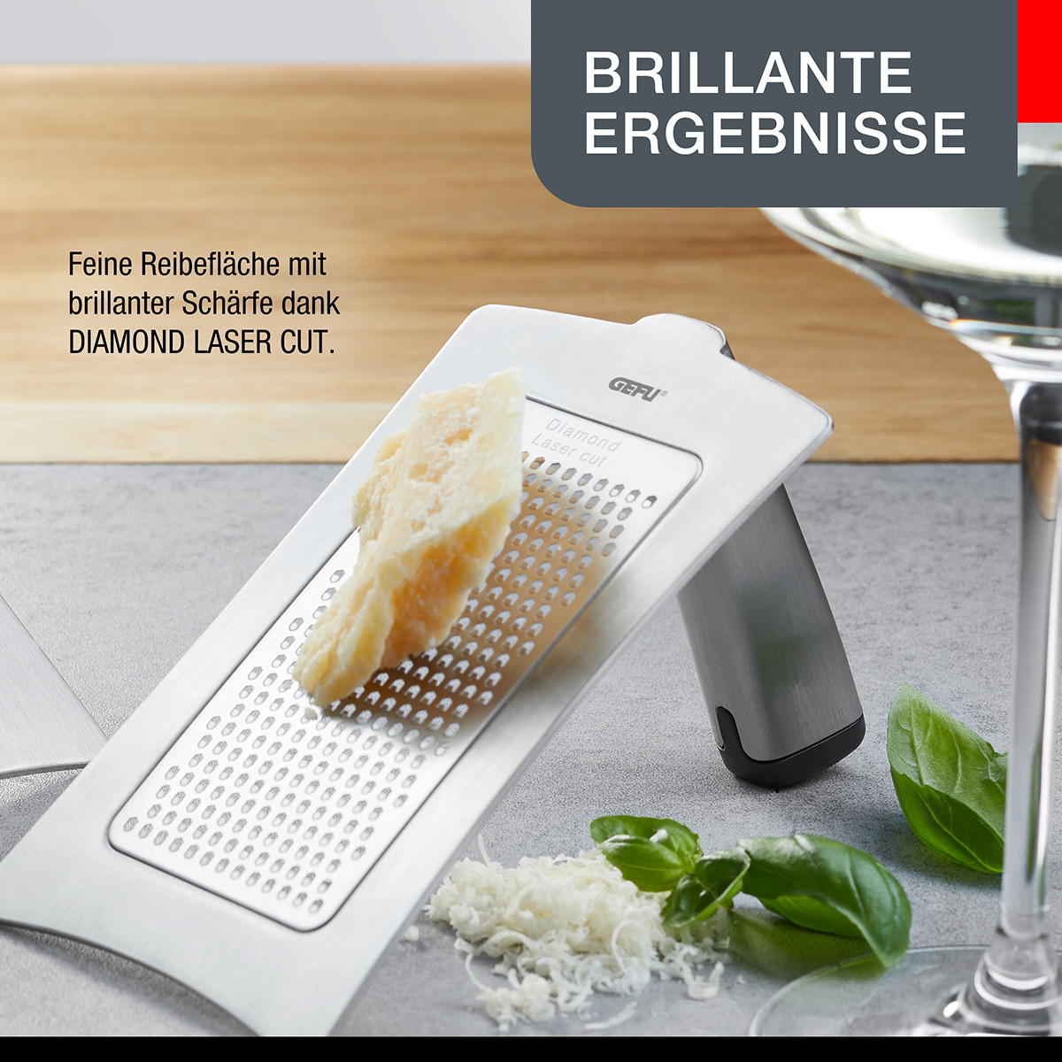 Ein Edelstahlreibe mit Käse und geriebenem Käse. Die Reibe hat einen silbernen Griff und eine diamantgeschliffene Oberfläche.