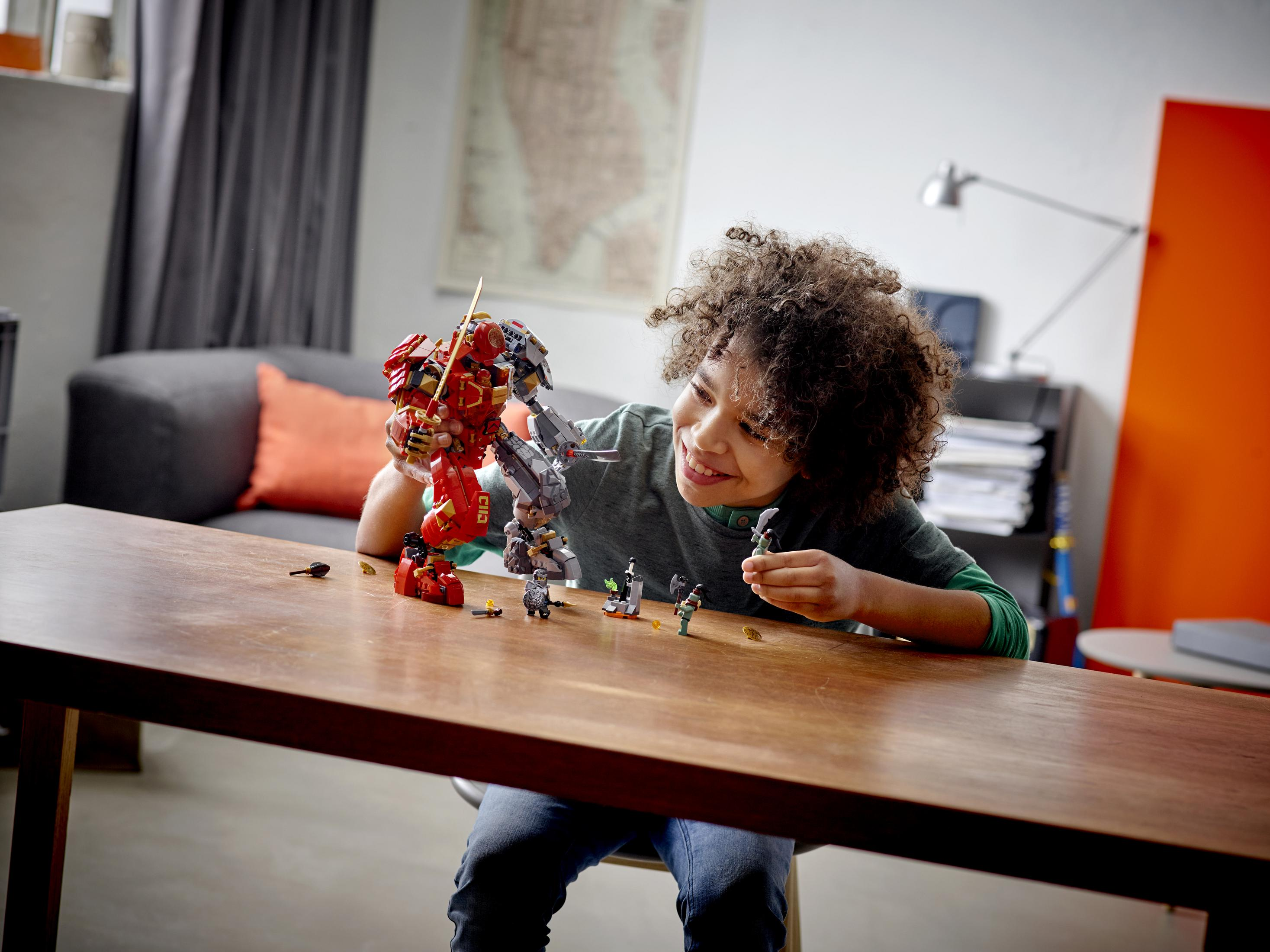 Junge spielt mit LEGOs, baut einen Roboter, mit anderen LEGO-Teilen auf einem Tisch.