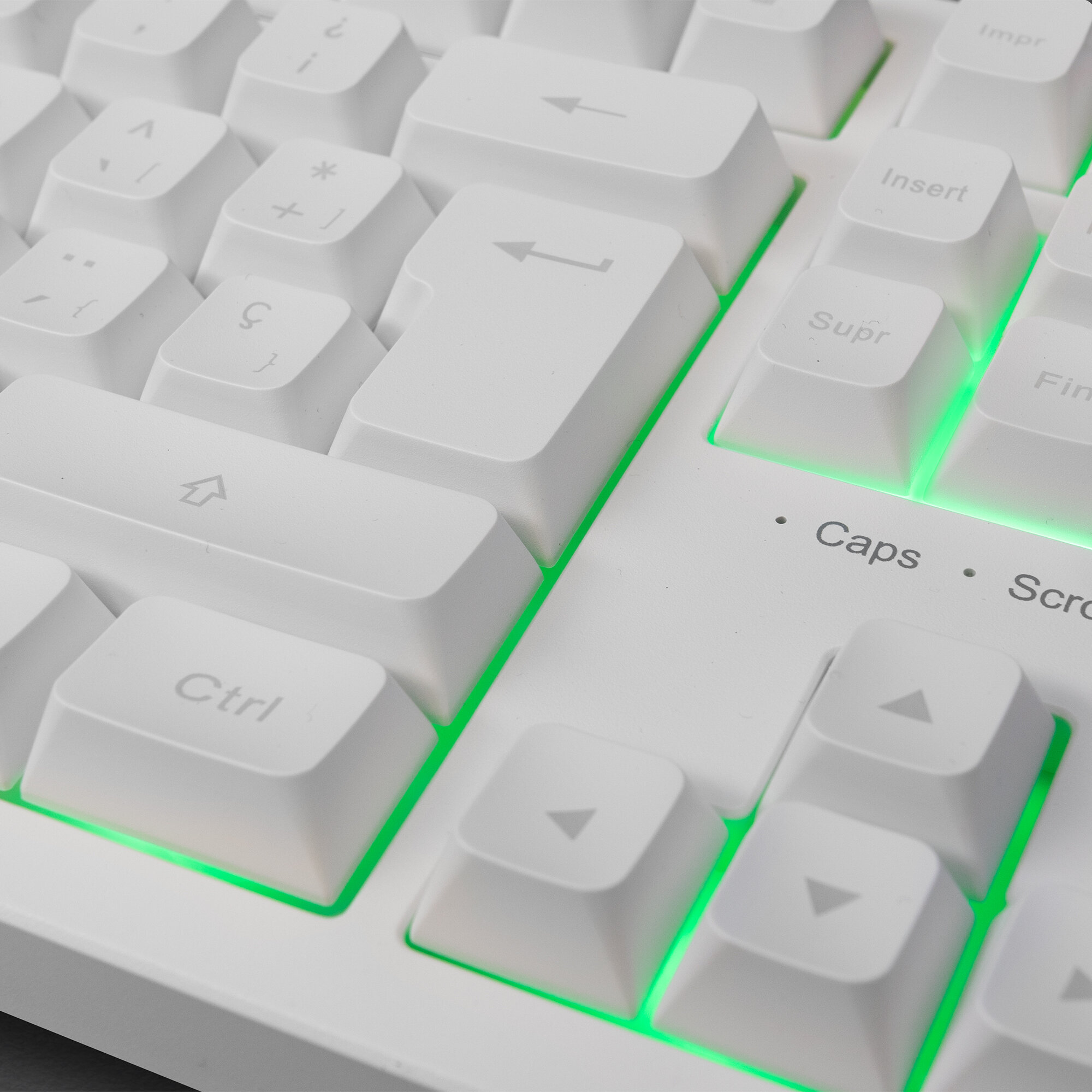 Primo piano di una tastiera bianca con retroilluminazione verde. Tasti includono Ctrl, Caps Lock e tasti freccia.