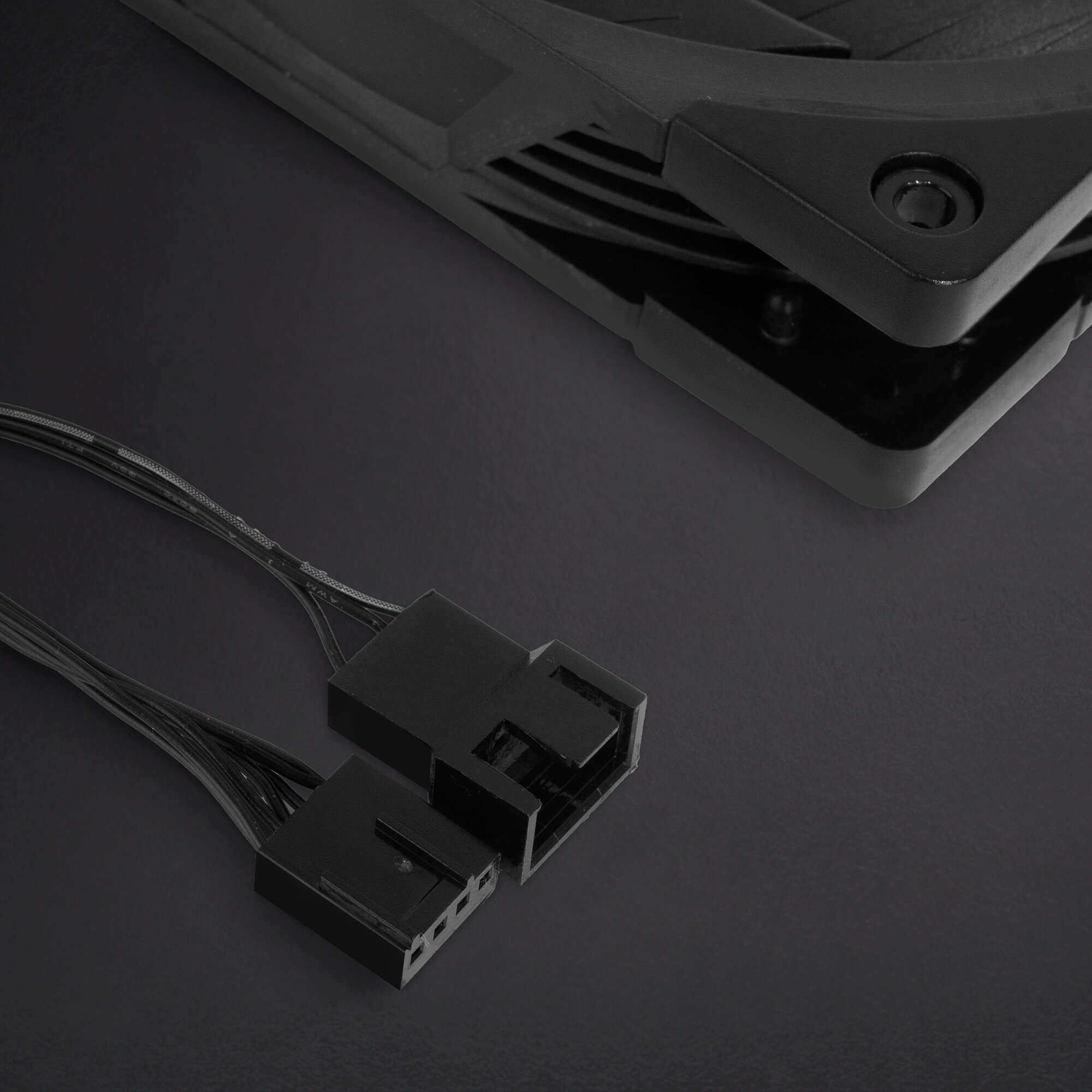 Zbliżenie czarnych złączy wentylatora. Dwa złącza z wieloma przewodami na czarnej powierzchni.