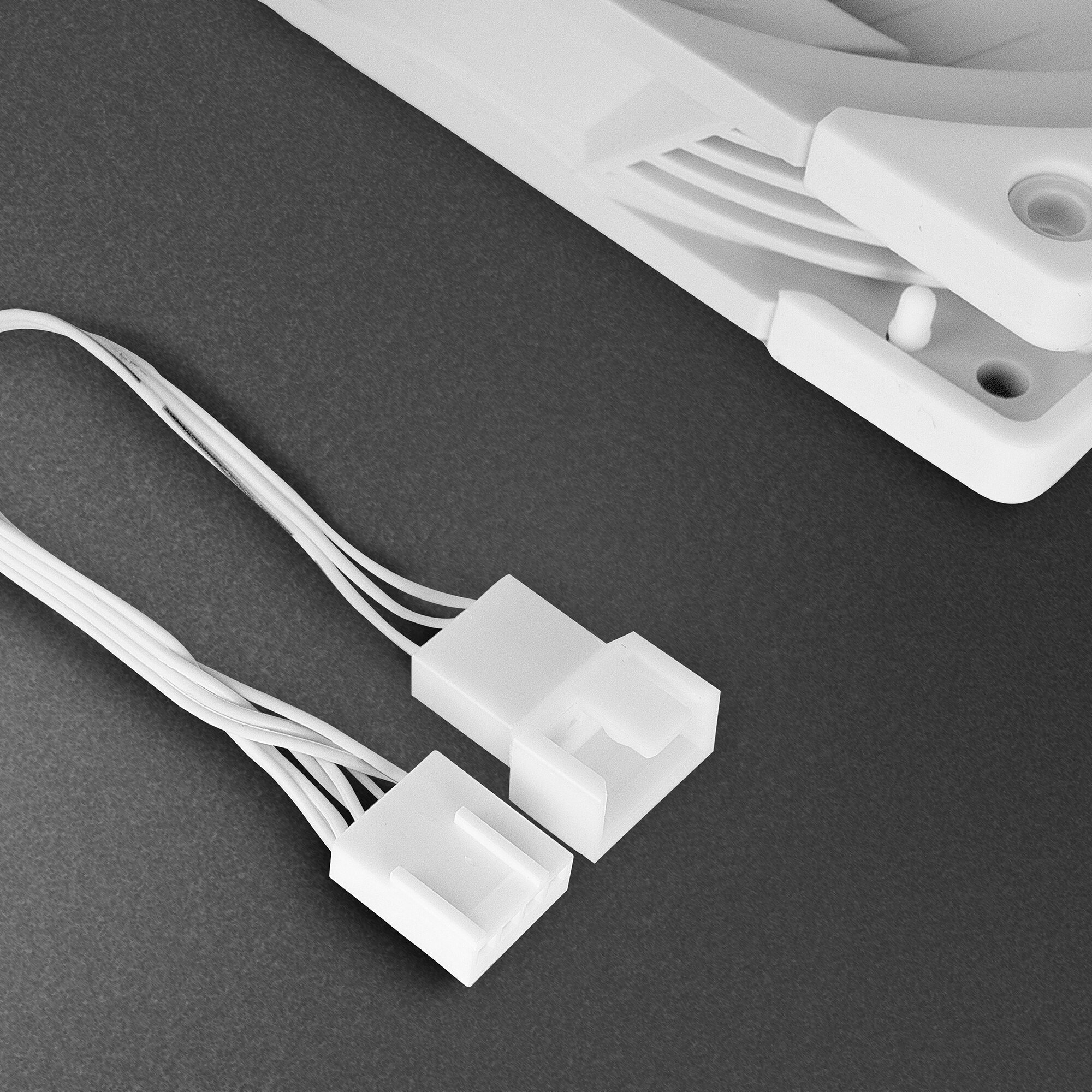 Dwa białe złącza wentylatora z wieloma białymi przewodami na ciemnoszarym tle.