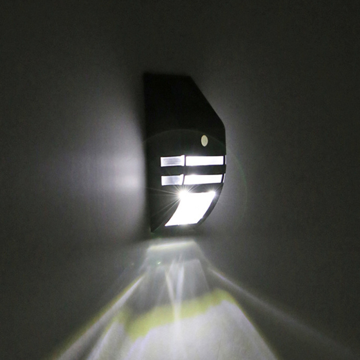 Schwarze Außenleuchte an einer Wand, die nach unten leuchtet. Licht scheint von der Vorderseite der Leuchte.