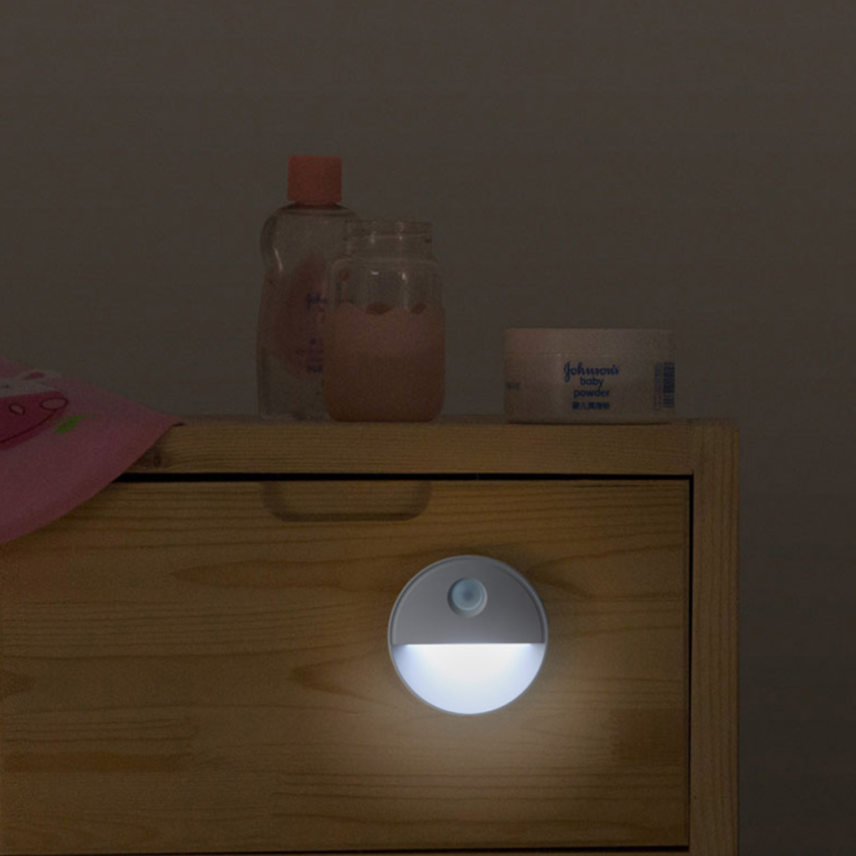 Ein Nachtlicht auf einem hölzernen Nachttisch neben Lotion und Babypuder.