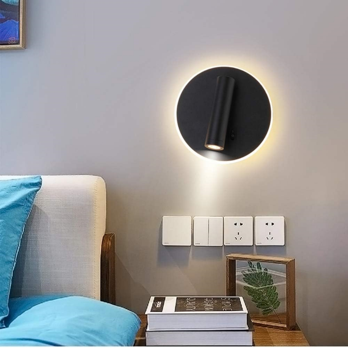 Wandmontierte schwarze Lampe mit rundem Sockel, die Licht aussendet, grauer Hintergrund.