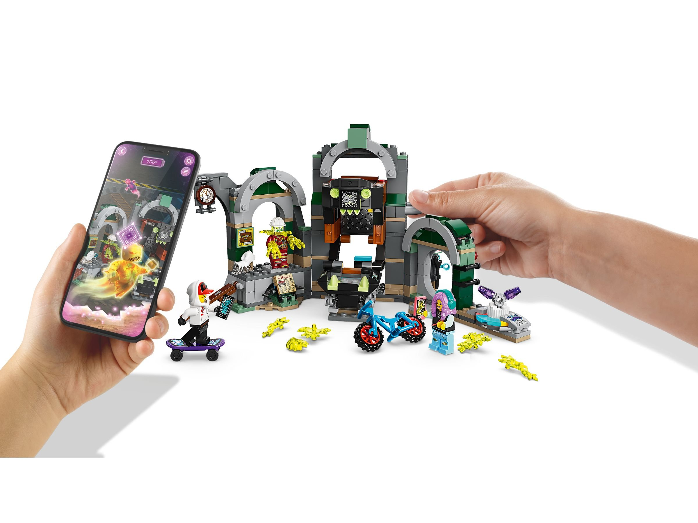 Zestaw Lego z dzieckiem trzymającym telefon pokazującym ducha. Obecny jest deskorolkarz i rower.