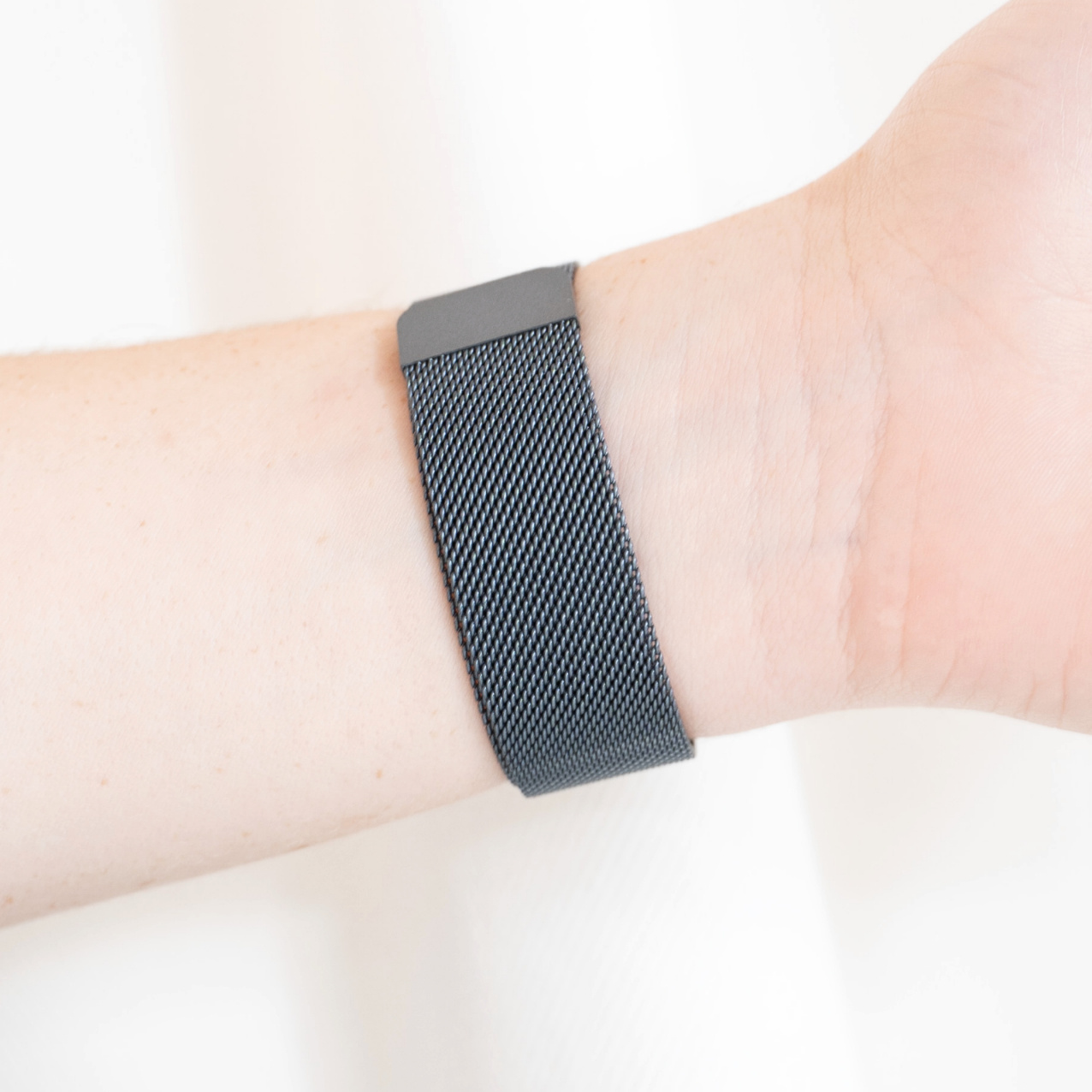 Das Handgelenk einer Person mit einem schwarzen Mesh-Uhrenarmband.