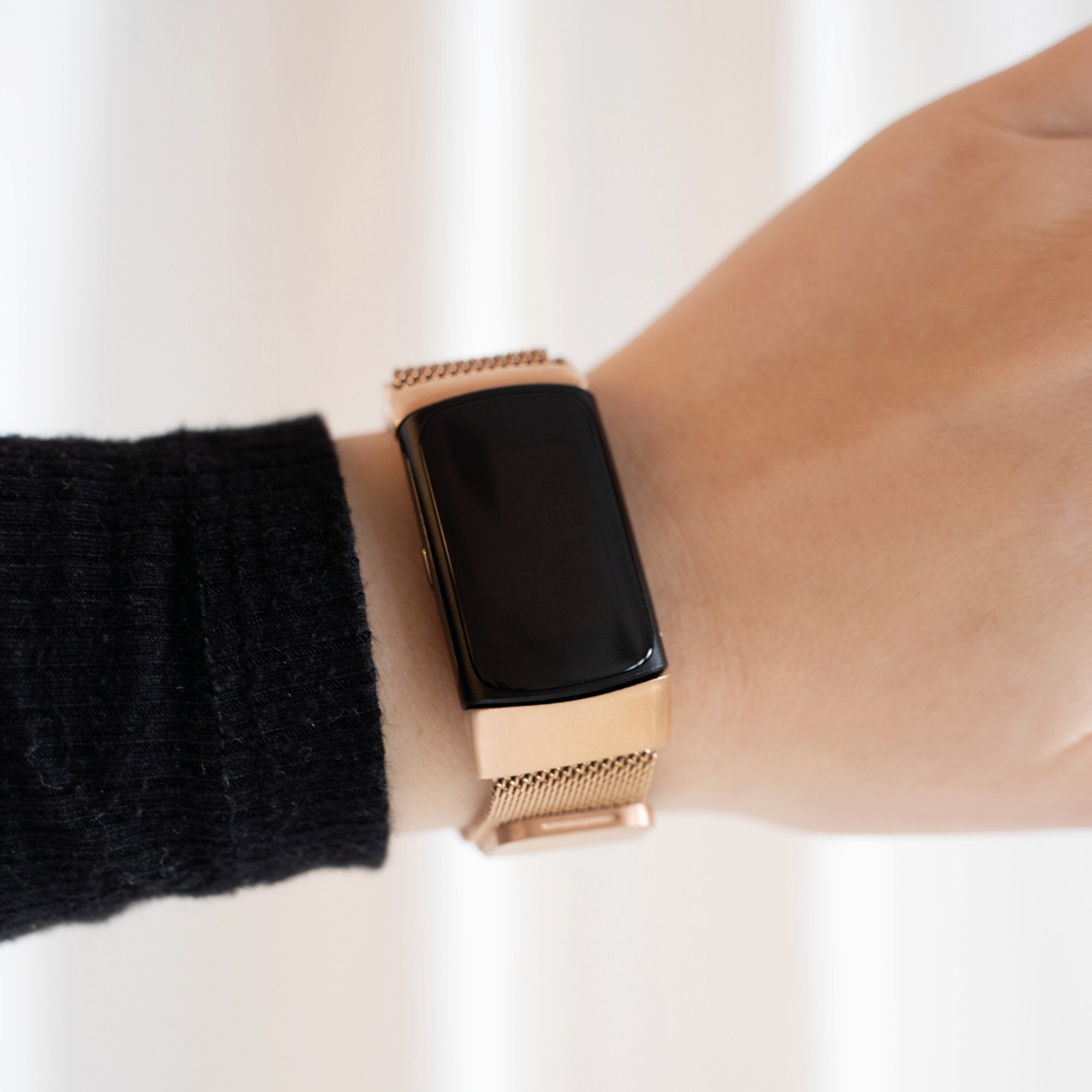Handgelenk mit goldener Uhr, zeigt einen schwarzen Bildschirm. Das Armband ist goldfarben und meshartig.