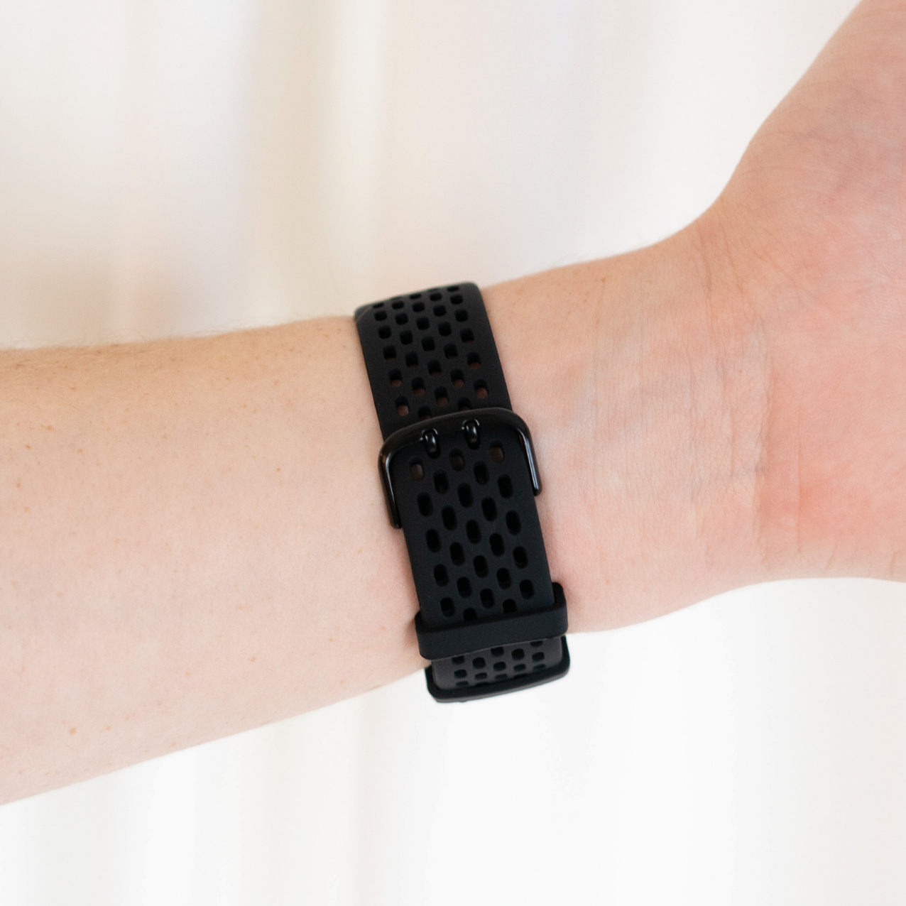 Schwarzes Armband am Handgelenk. Zeigt die Schnalle und das Design des Bands.