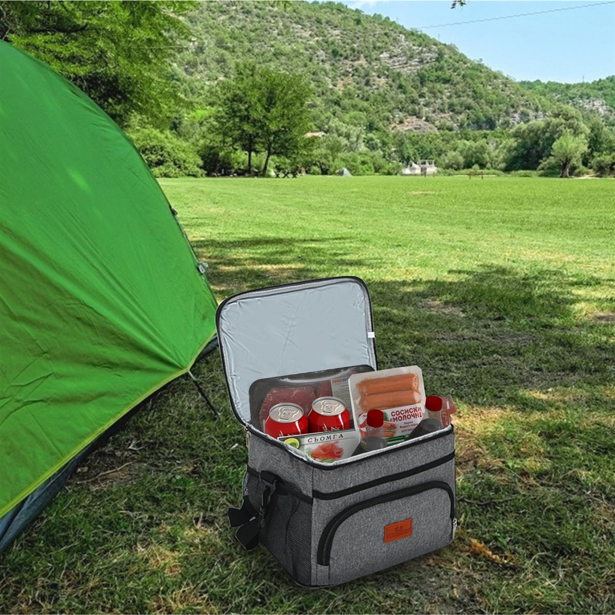 Geöffnete Kühltasche auf Gras mit Lebensmitteln, in der Nähe eines grünen Zeltes und Berges.