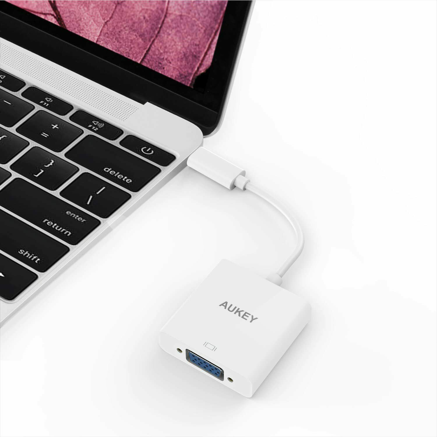Ein weißer AUKEY-Adapter, der mit einem Laptop verbunden ist. Er hat einen VGA-Anschluss.