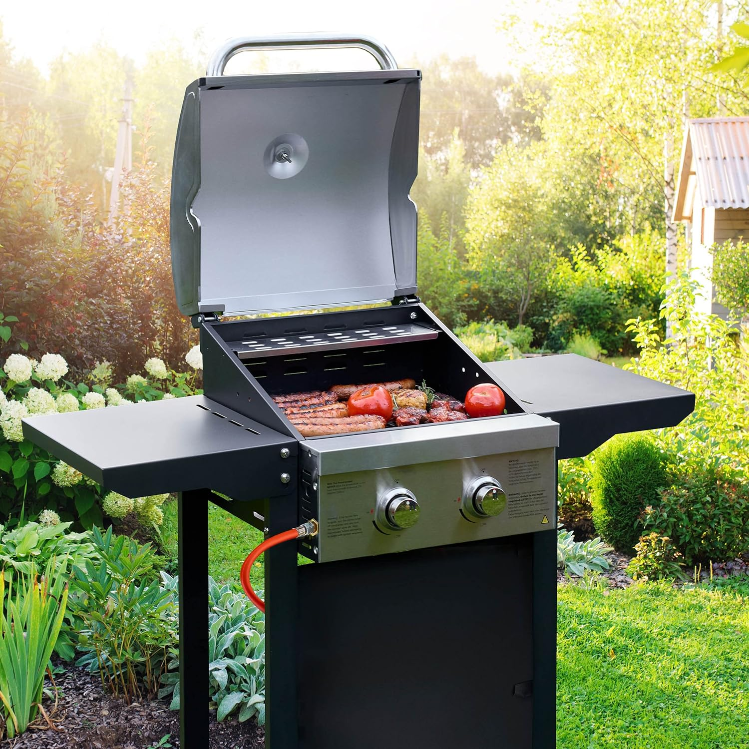 Grill mit Essen darauf. Der Grill ist geöffnet und hat Steaks, Tomaten und Würstchen.