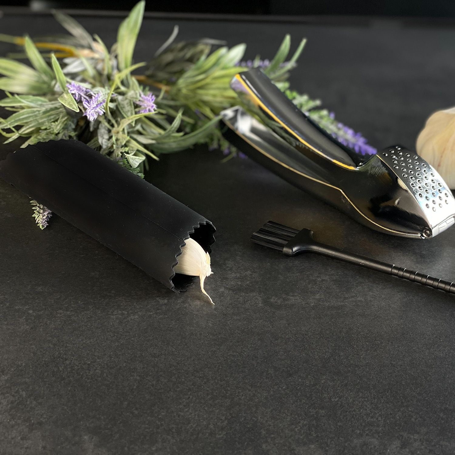 Knoblauch und Werkzeuge auf dunkler Oberfläche. Schwarz und Silber.