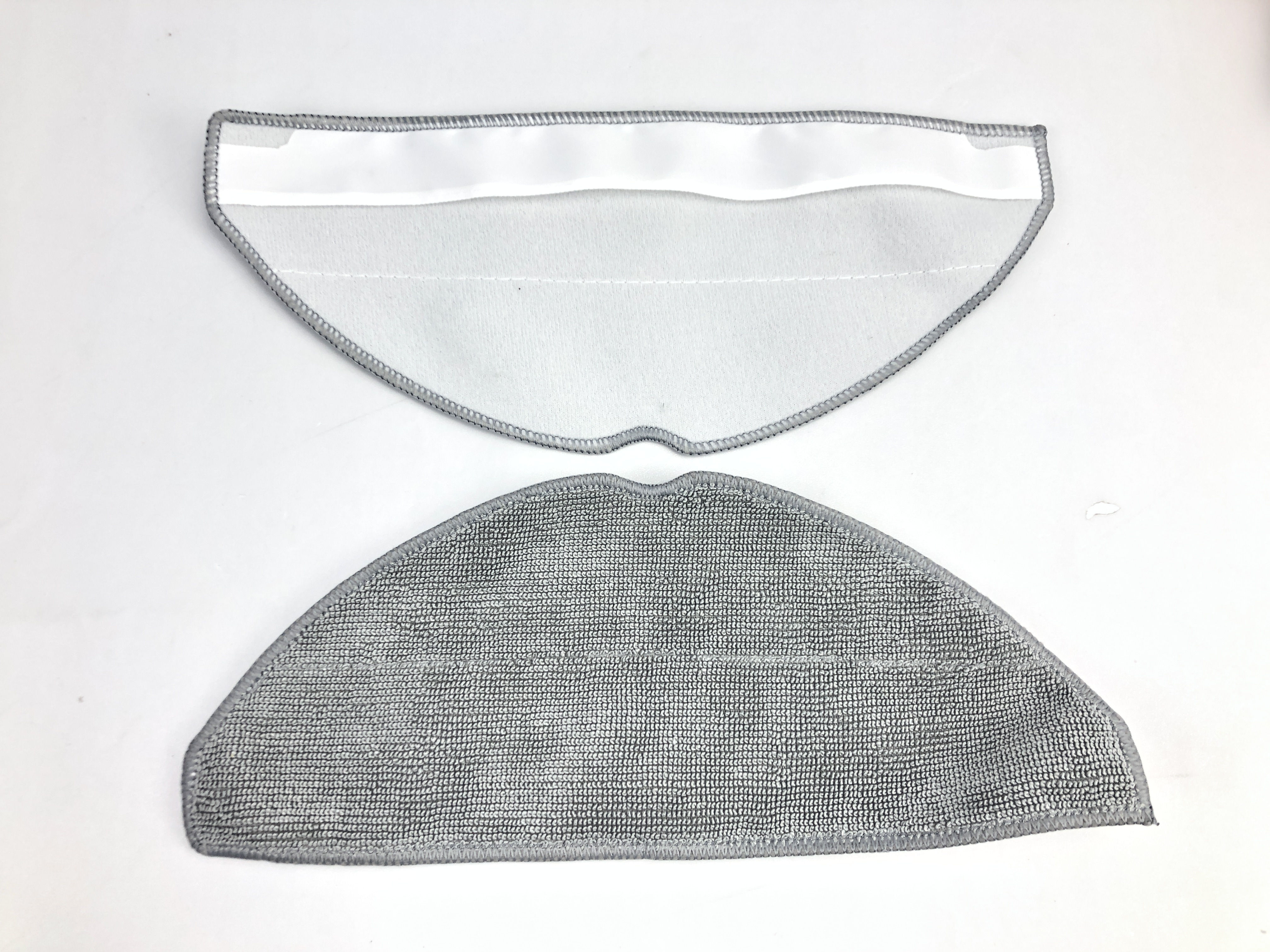 Dwie szare nakładki do mopa dla robota sprzątającego, jedna złożona na drugiej, na białej powierzchni.