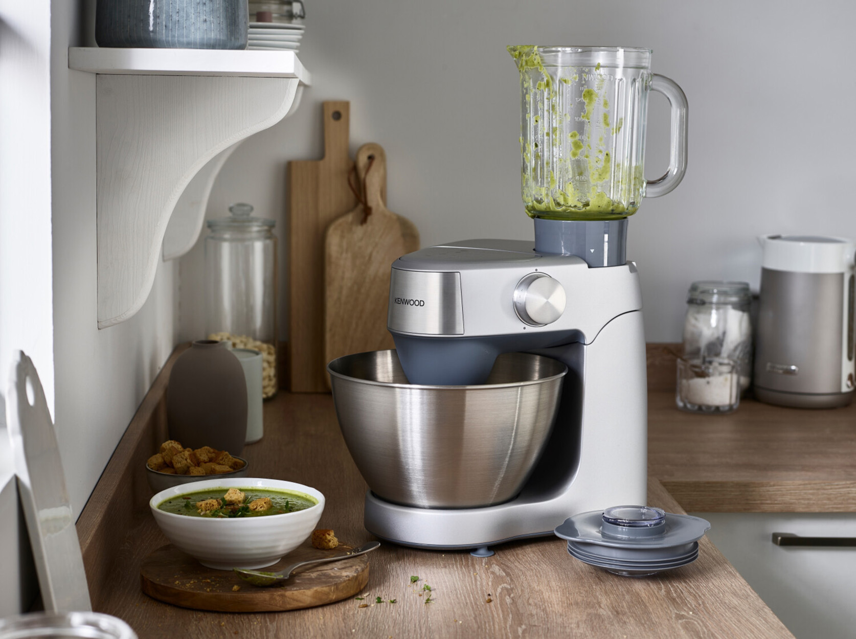 Eine Kenwood Küchenmaschine mit einer Schüssel Suppe. Schneidebretter und Zutaten sind sichtbar.