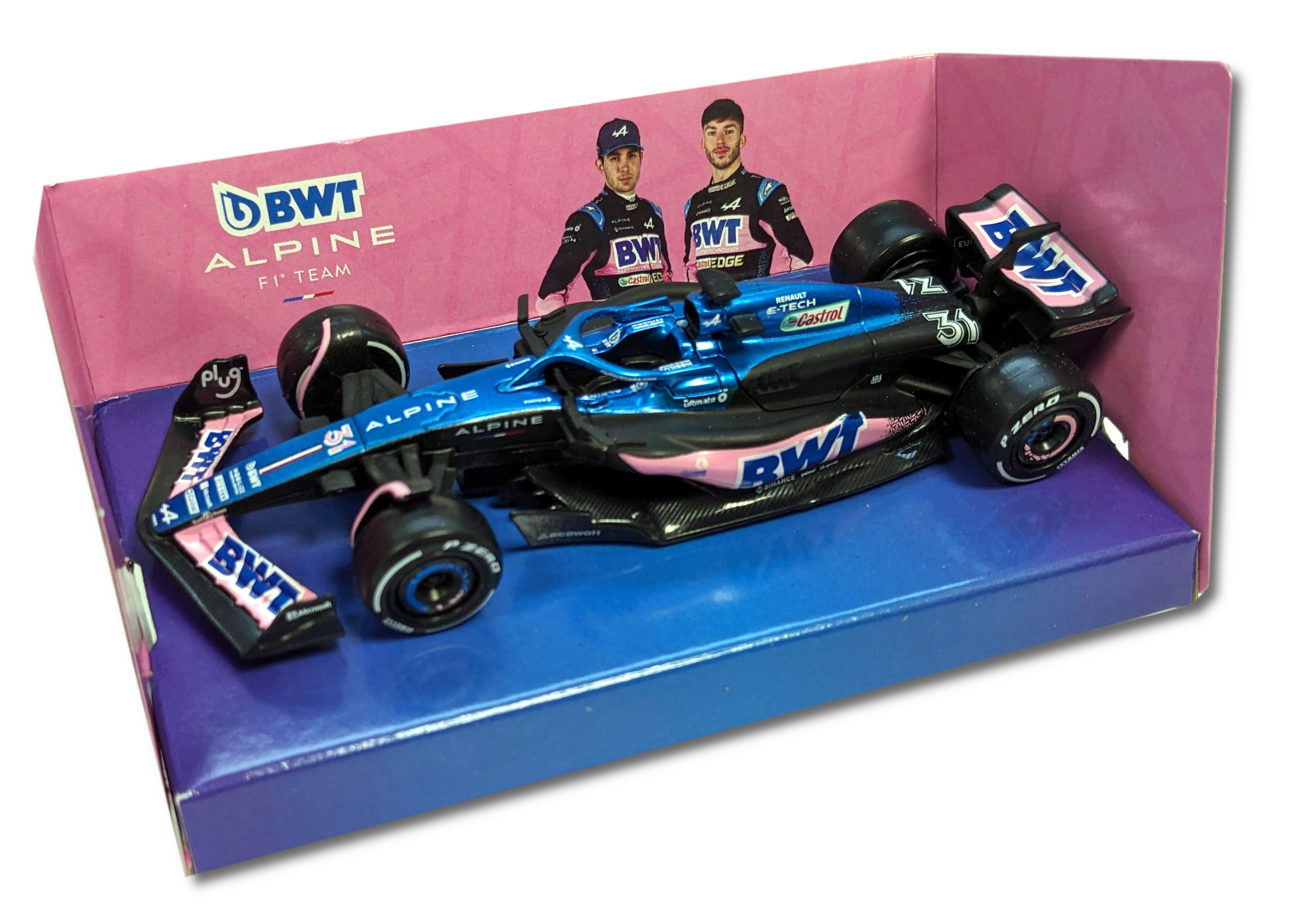 Ein Spielzeug-Rennwagen in einer Box. Die Box hat Bilder der Fahrer und des Teamlogos. Das Auto ist blau und rosa.