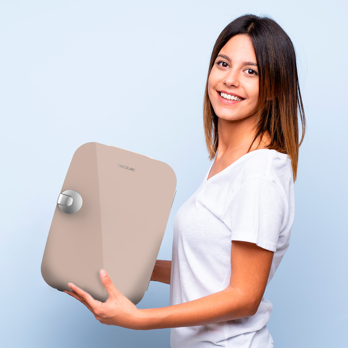 Mujer sosteniendo un electrodoméstico beige, sonriendo a la cámara.