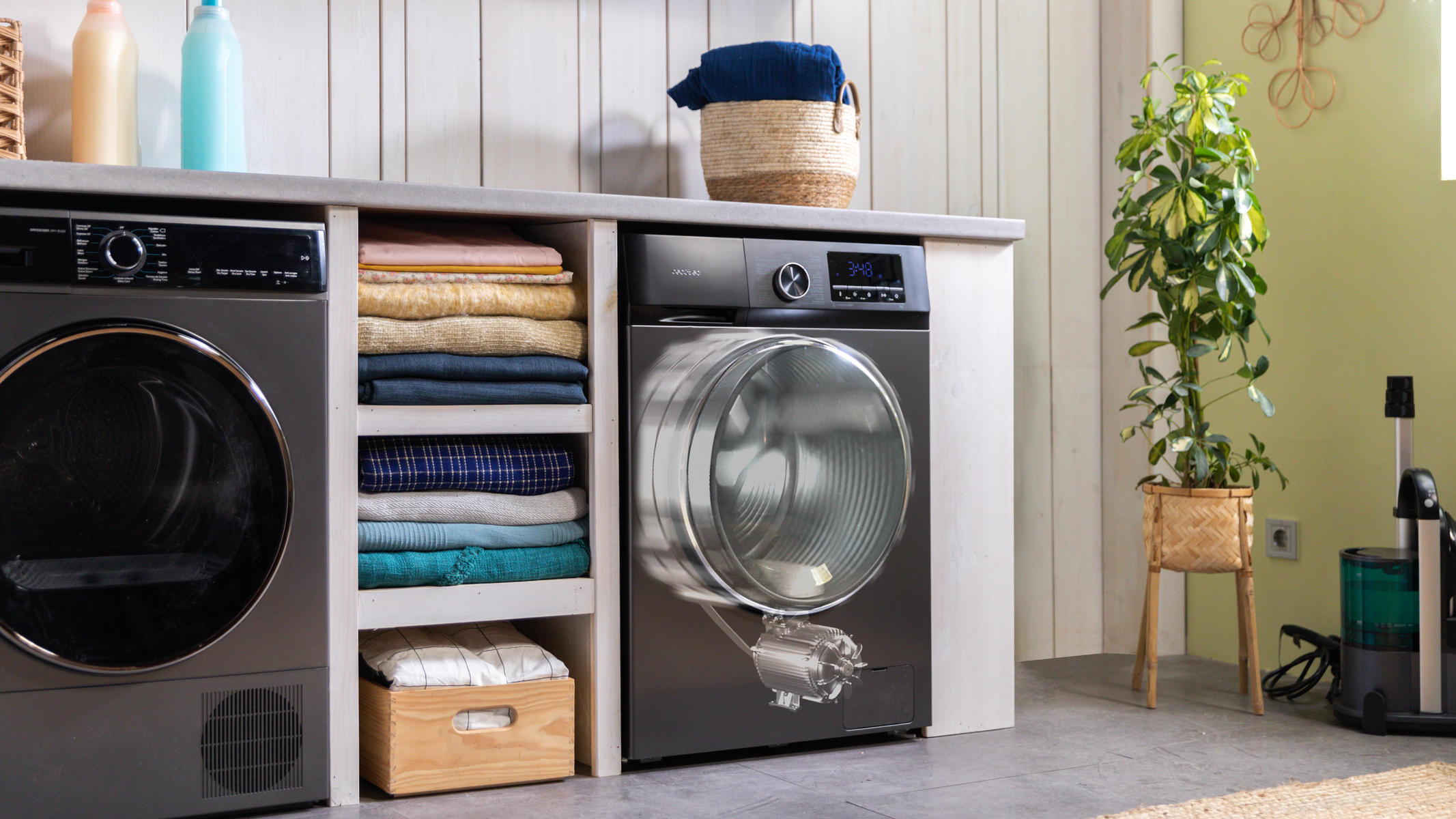 Pralnia z pralką, suszarką, ułożonymi ubraniami i rośliną doniczkową.