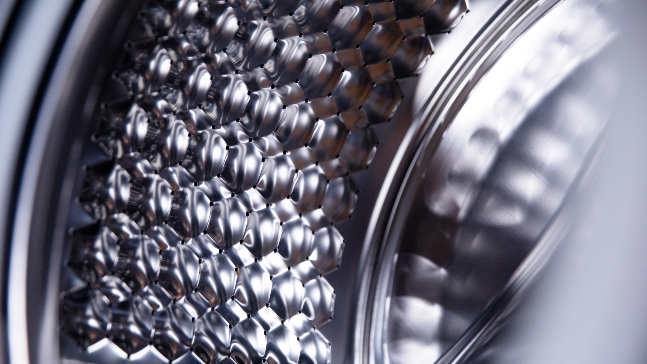 Zbliżenie wnętrza bębna pralki, pokazujące sześciokątny wzór.