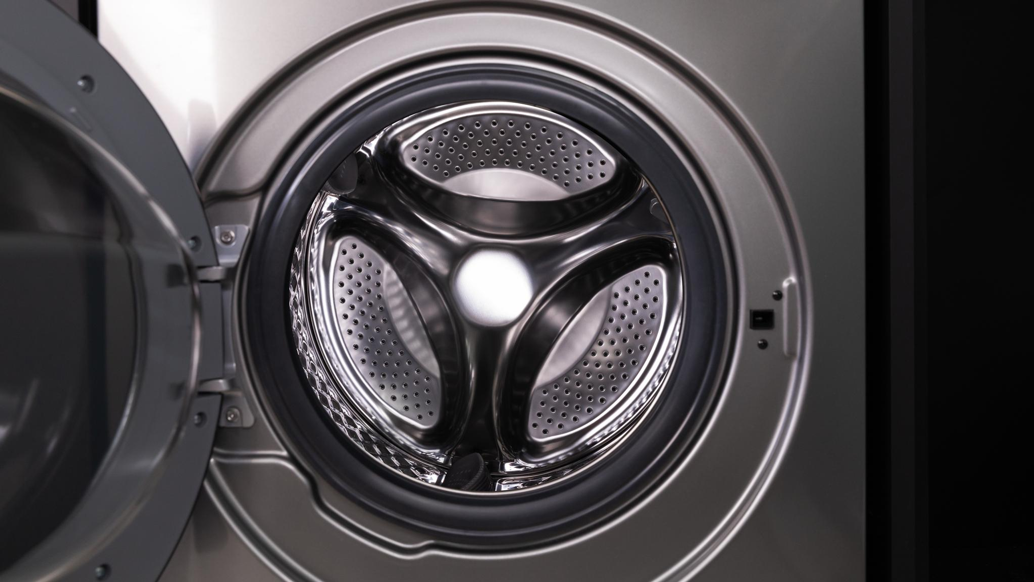 Zbliżenie bębna pralki, otwartego. Wnętrze ze stali nierdzewnej z trójramiennym designem.