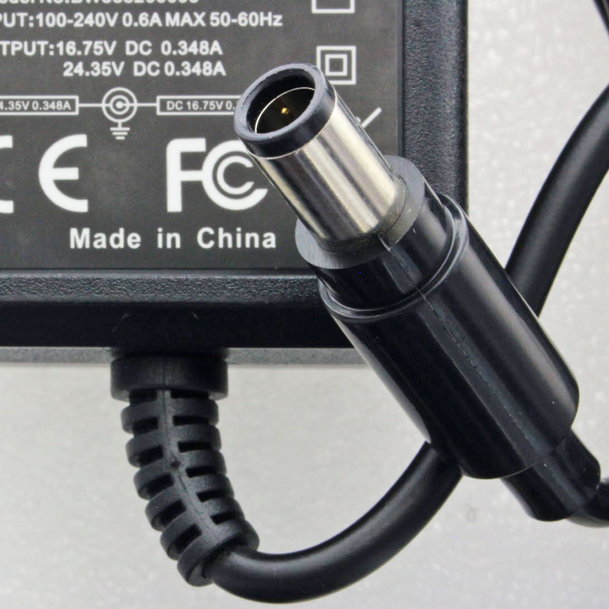 Schwarzer Netzadapter mit rundem Stecker. Kabel und Details auf schwarzem Hintergrund.