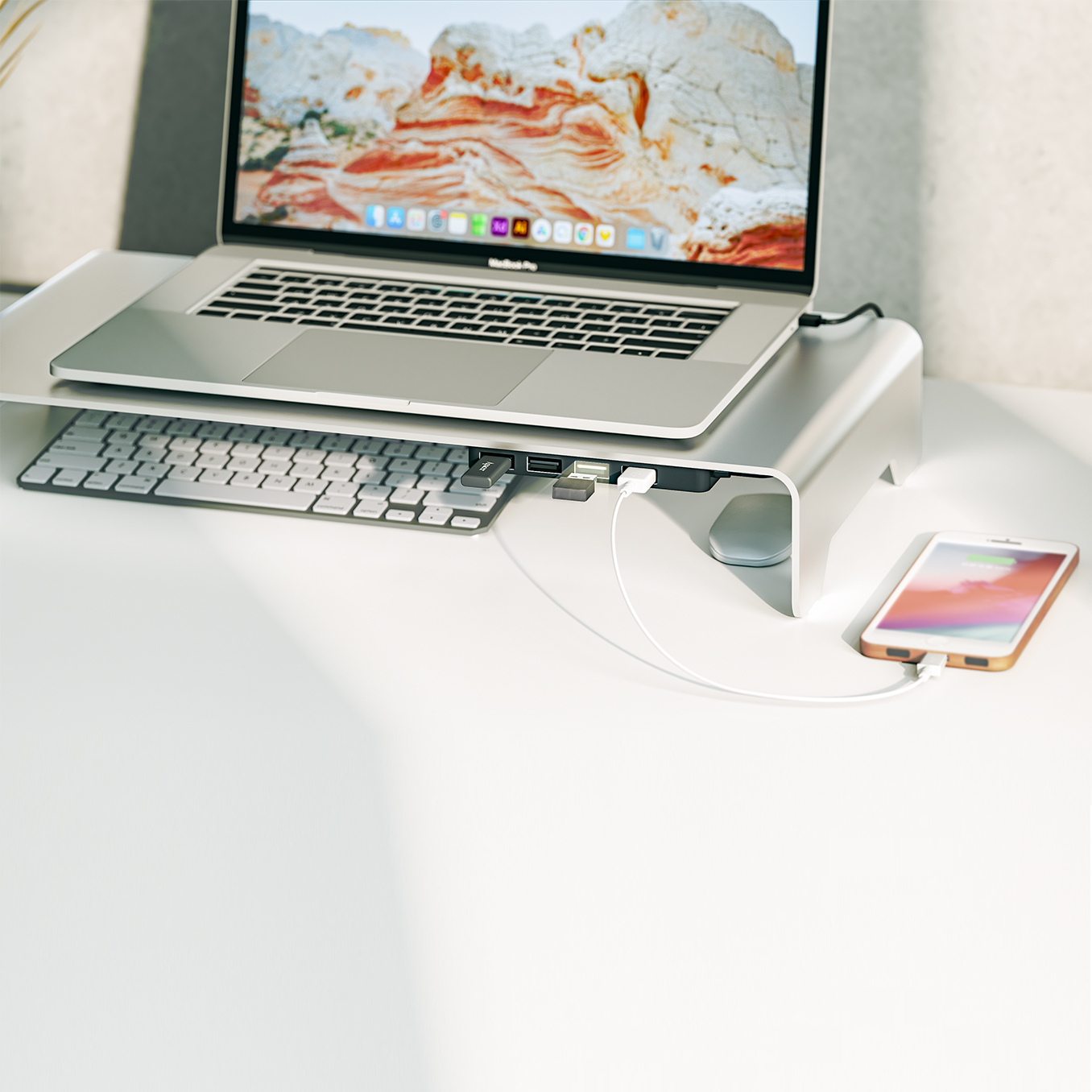 Laptop, Tastatur, Telefon, das auf einem weißen Schreibtisch geladen wird, mit einem Schreibtischständer.