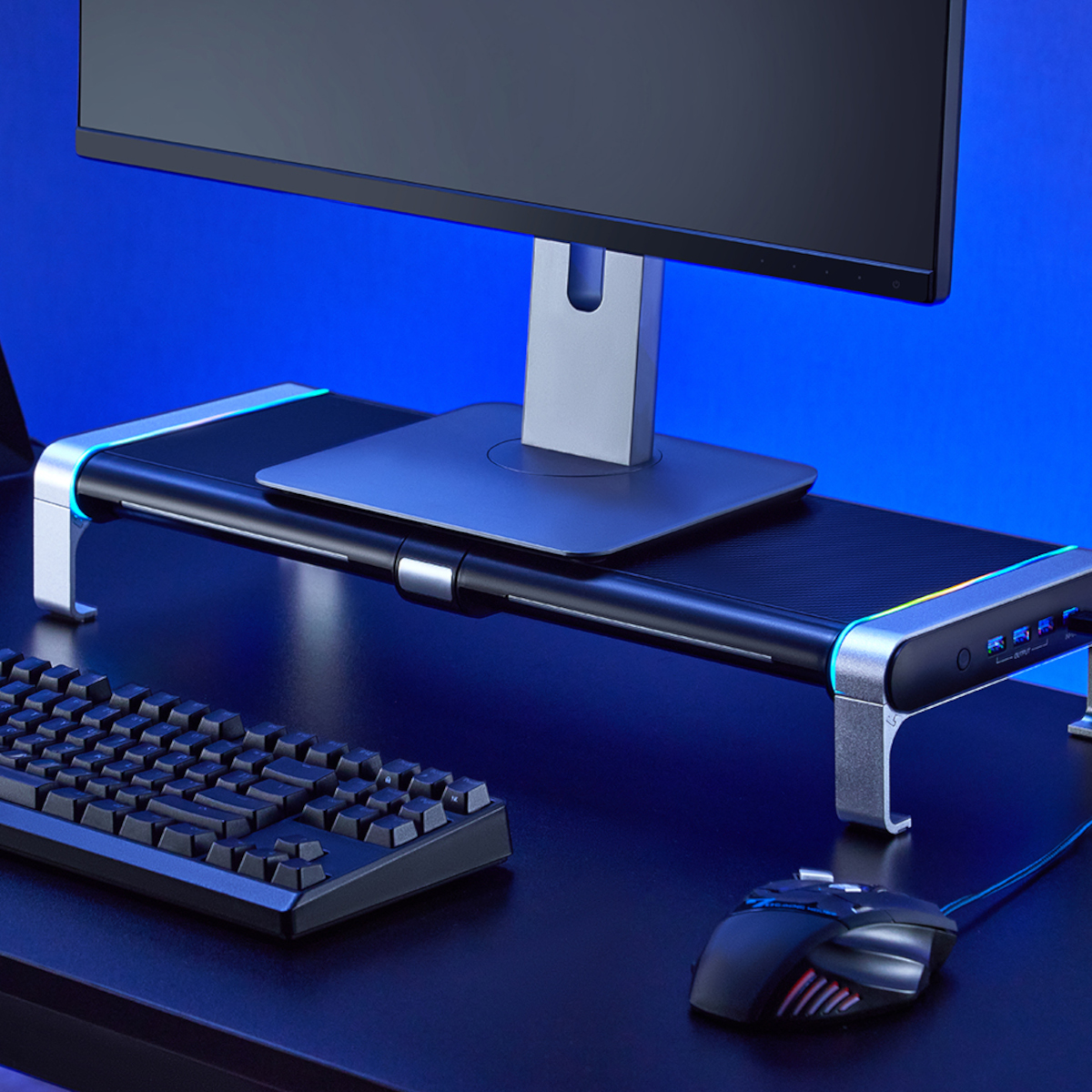 Schwarzes Schreibtisch-Setup mit Monitor, Ständer, Tastatur und Maus.