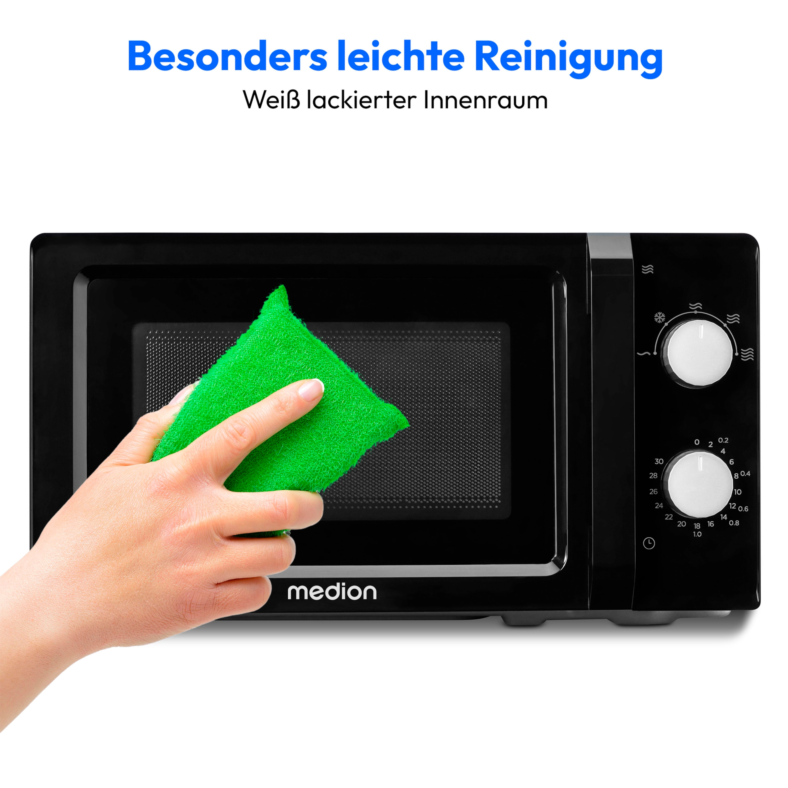 Ręka czyszcząca czarną kuchenkę mikrofalową zieloną gąbką.