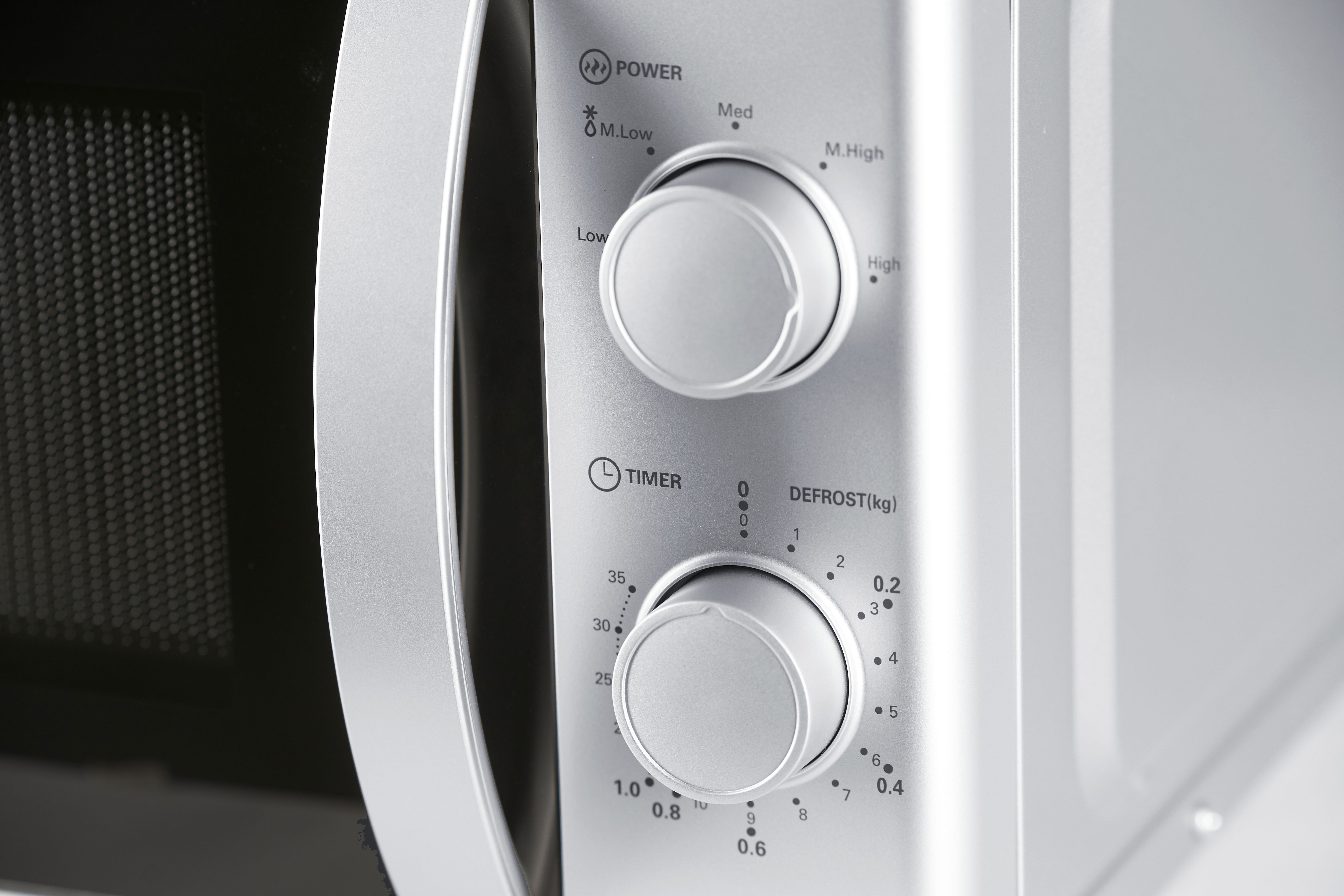Close-up of a microwave control panel. Knobs for power, timer, and defrost are visible.