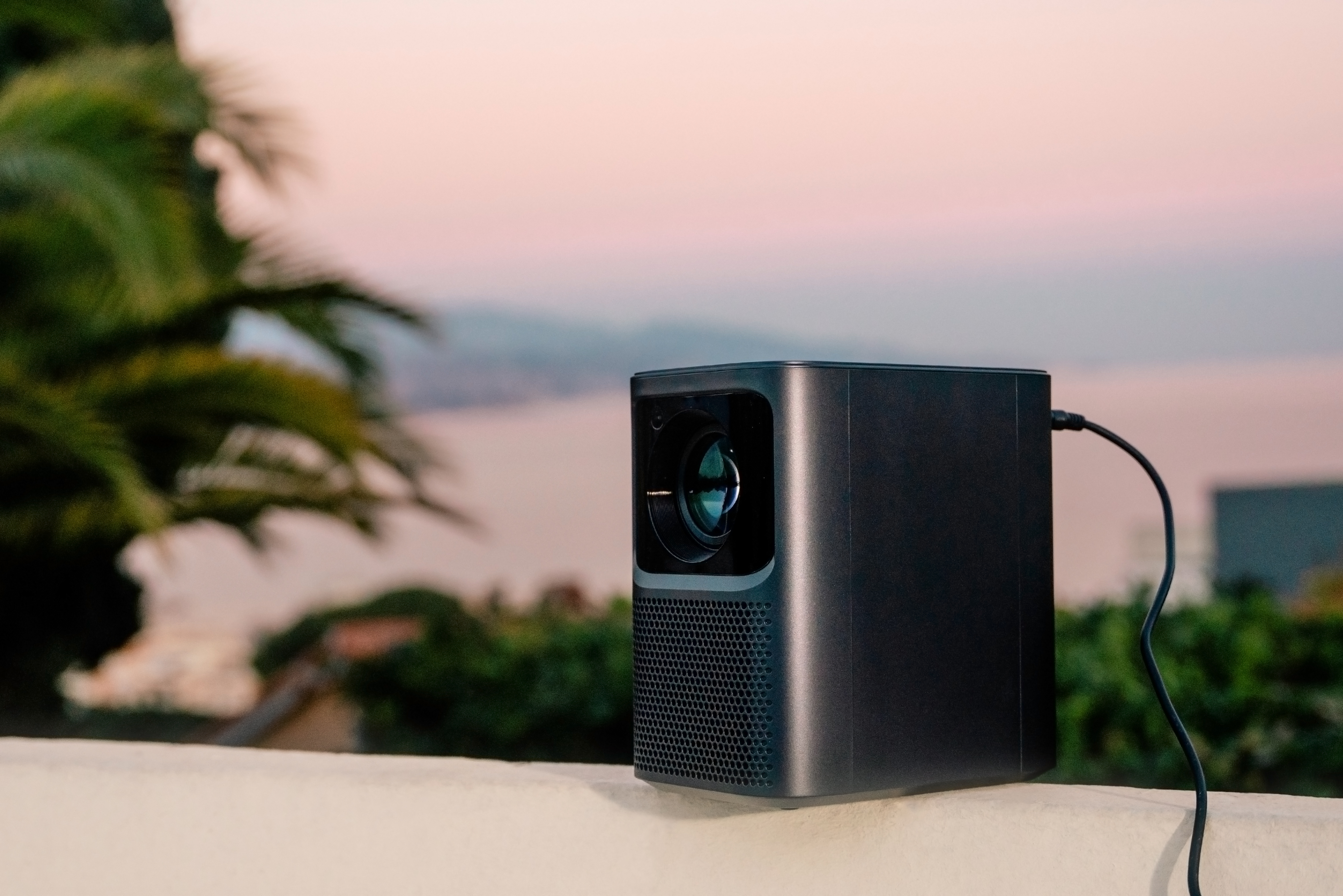 Czarny projektor na białej powierzchni, z pięknym krajobrazem morskim w tle.