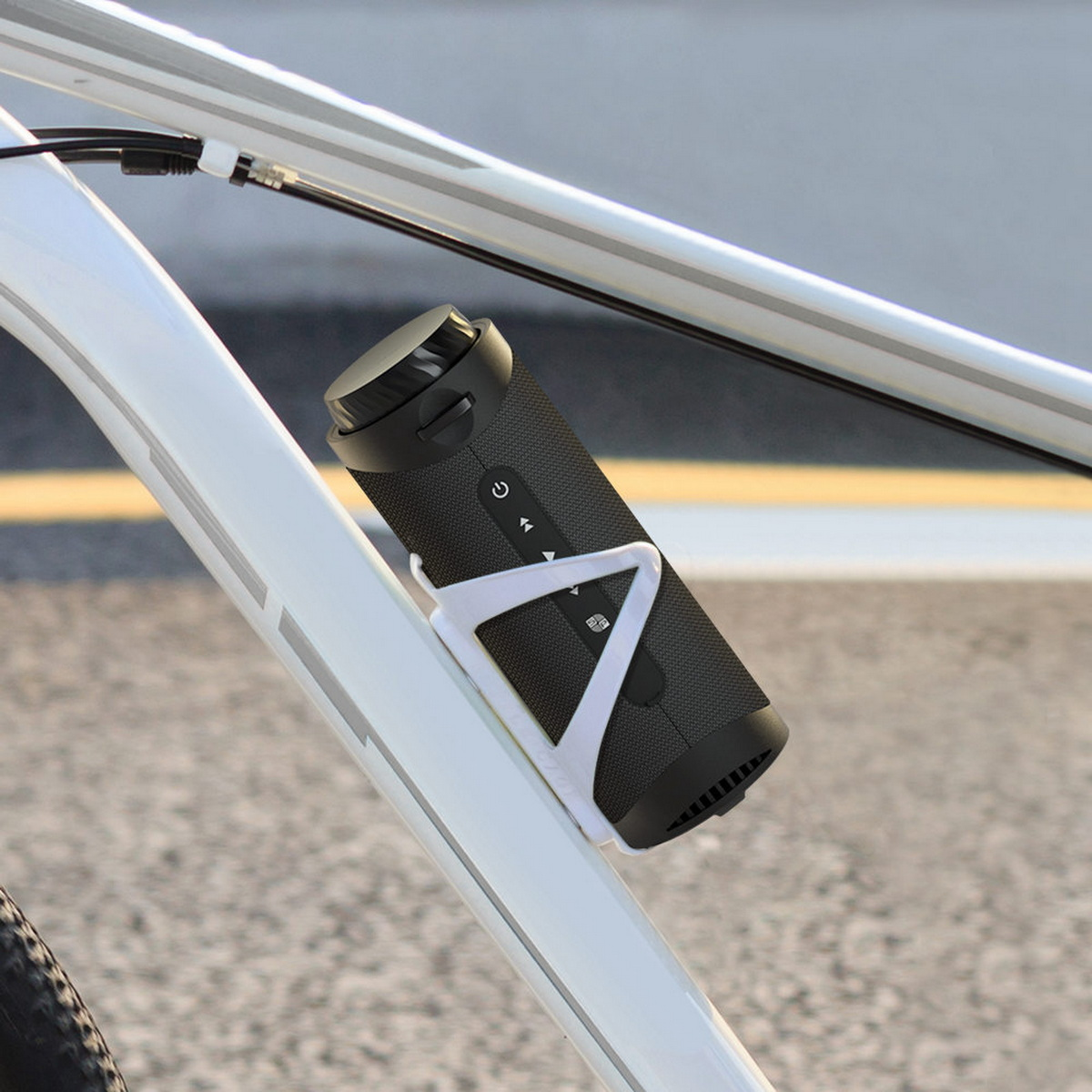 Czarny głośnik zamontowany na ramie roweru. Biały uchwyt trzyma głośnik na miejscu.