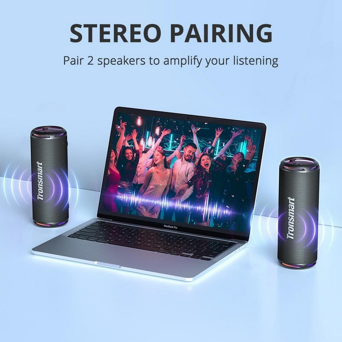 Zwei schwarze Lautsprecher flankieren einen Laptop, der eine Menschenmenge zeigt. Text lautet 'STEREO PAIRING'.