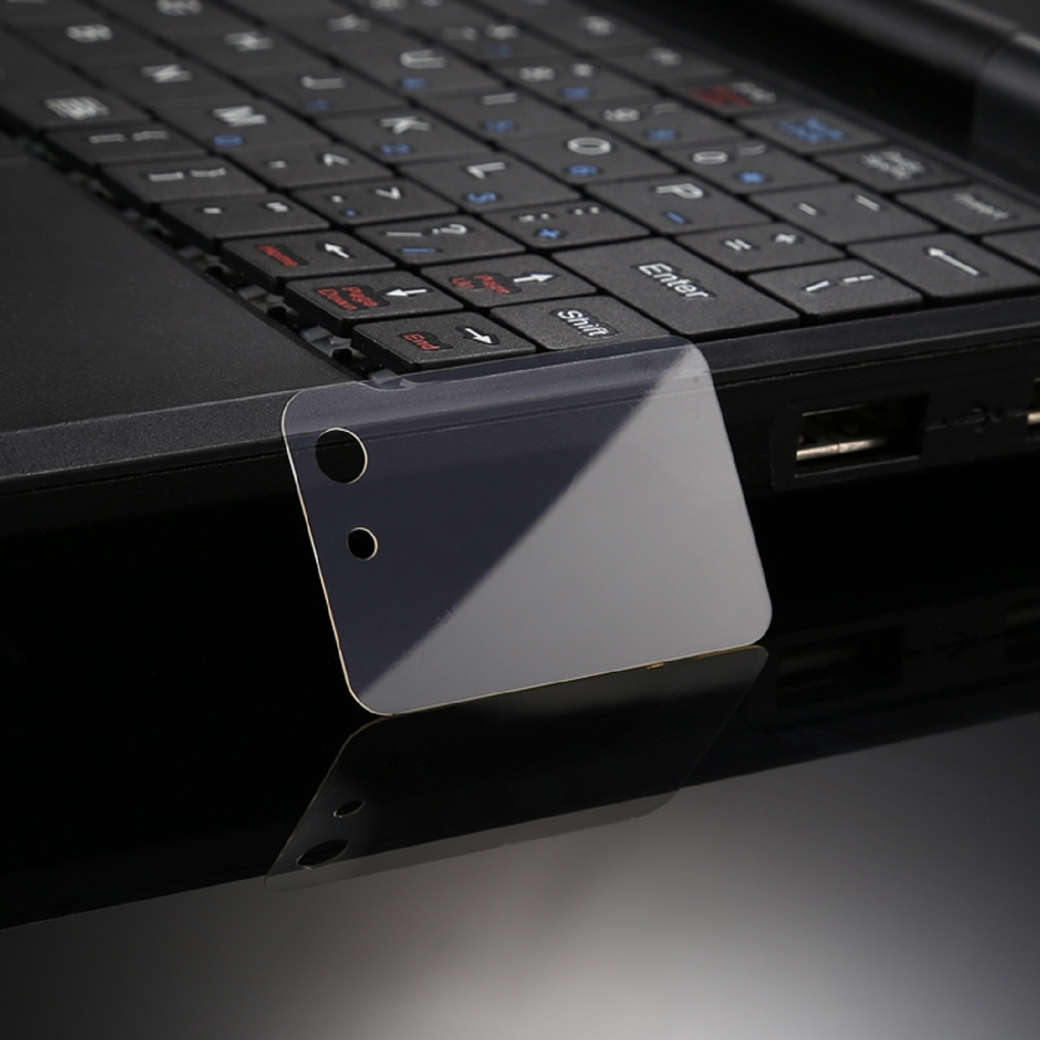 Eine Laptop-Tastatur mit einem Displayschutz oben, Nahaufnahme auf einer schwarzen Oberfläche.
