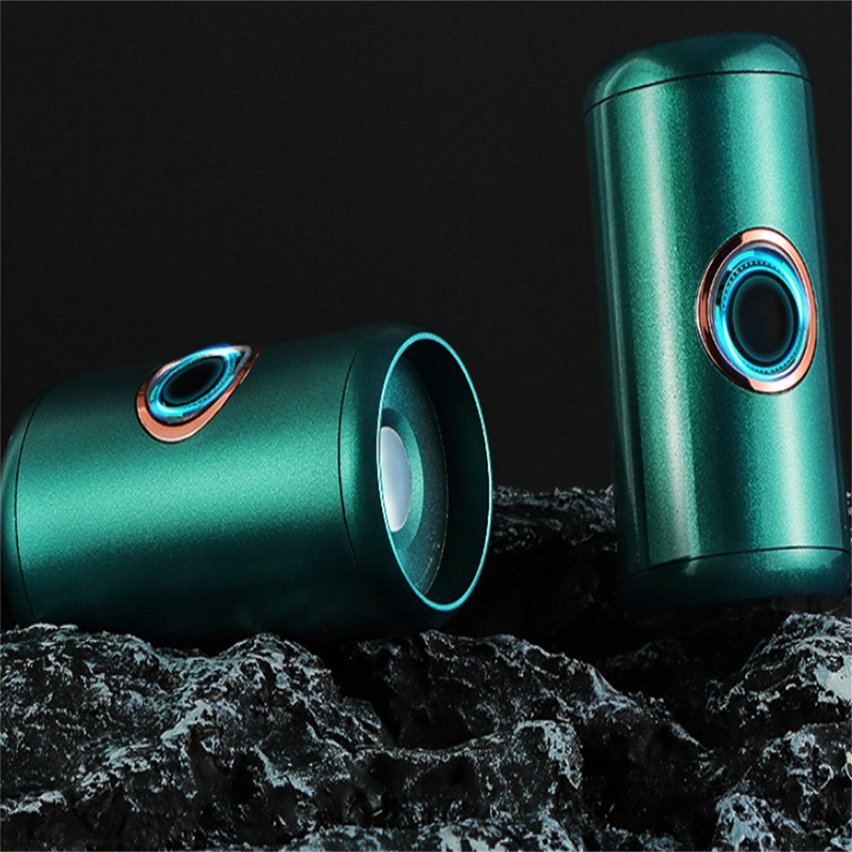 Zwei teal Zylinder mit leuchtenden blauen Ringen auf felsigem Untergrund, dunkler Hintergrund.