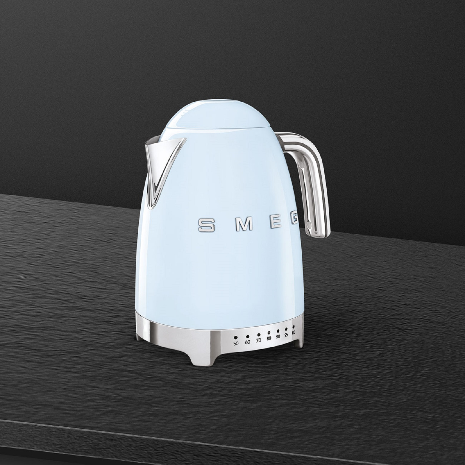 Hellblauer SMEG-Wasserkocher auf schwarzer Oberfläche. Silberne Akzente. Zahlen von 50 bis 100.