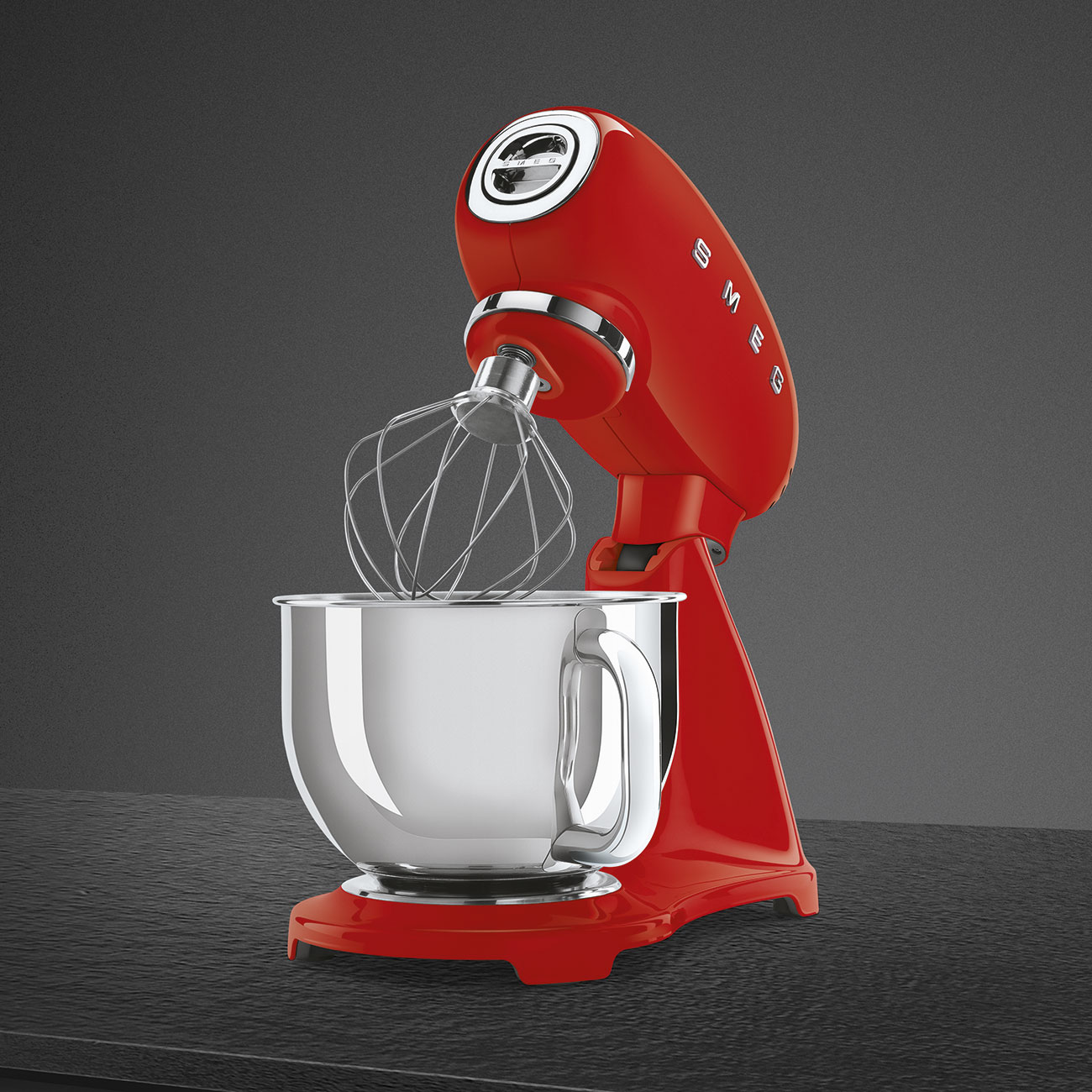Ein roter Smeg-Küchenmixer mit einer Edelstahlschüssel. Er steht auf einer dunklen Oberfläche.