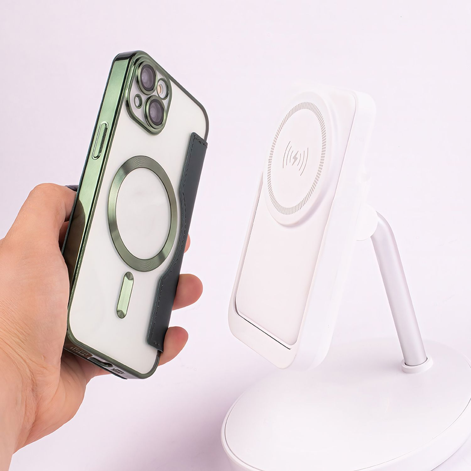 Mano che tiene una custodia per telefono, accanto a un supporto per caricabatterie wireless bianco con un telefono.