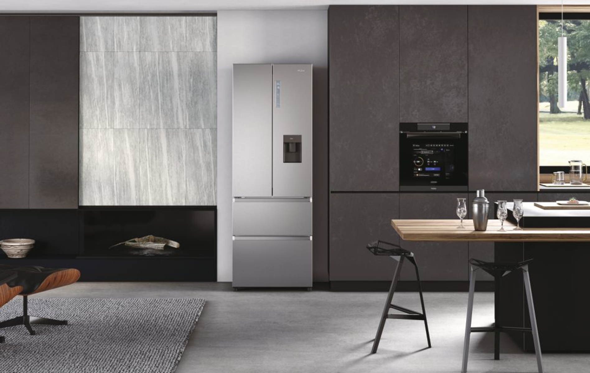 Una cocina moderna con nevera de acero inoxidable, armarios oscuros y encimera de madera con taburetes.