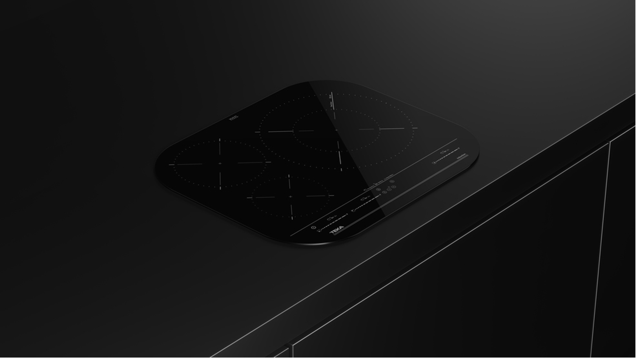 Czarna płyta indukcyjna na czarnym blacie. Widoczne są cztery strefy gotowania.