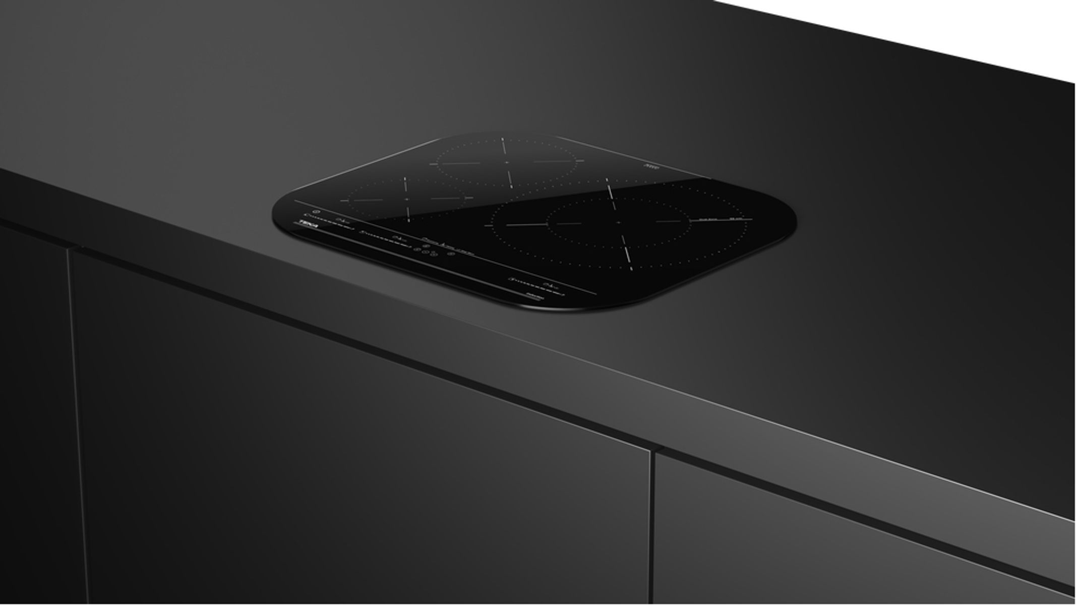 Czarna płyta indukcyjna zamontowana na czarnym blacie. Czarne tło.