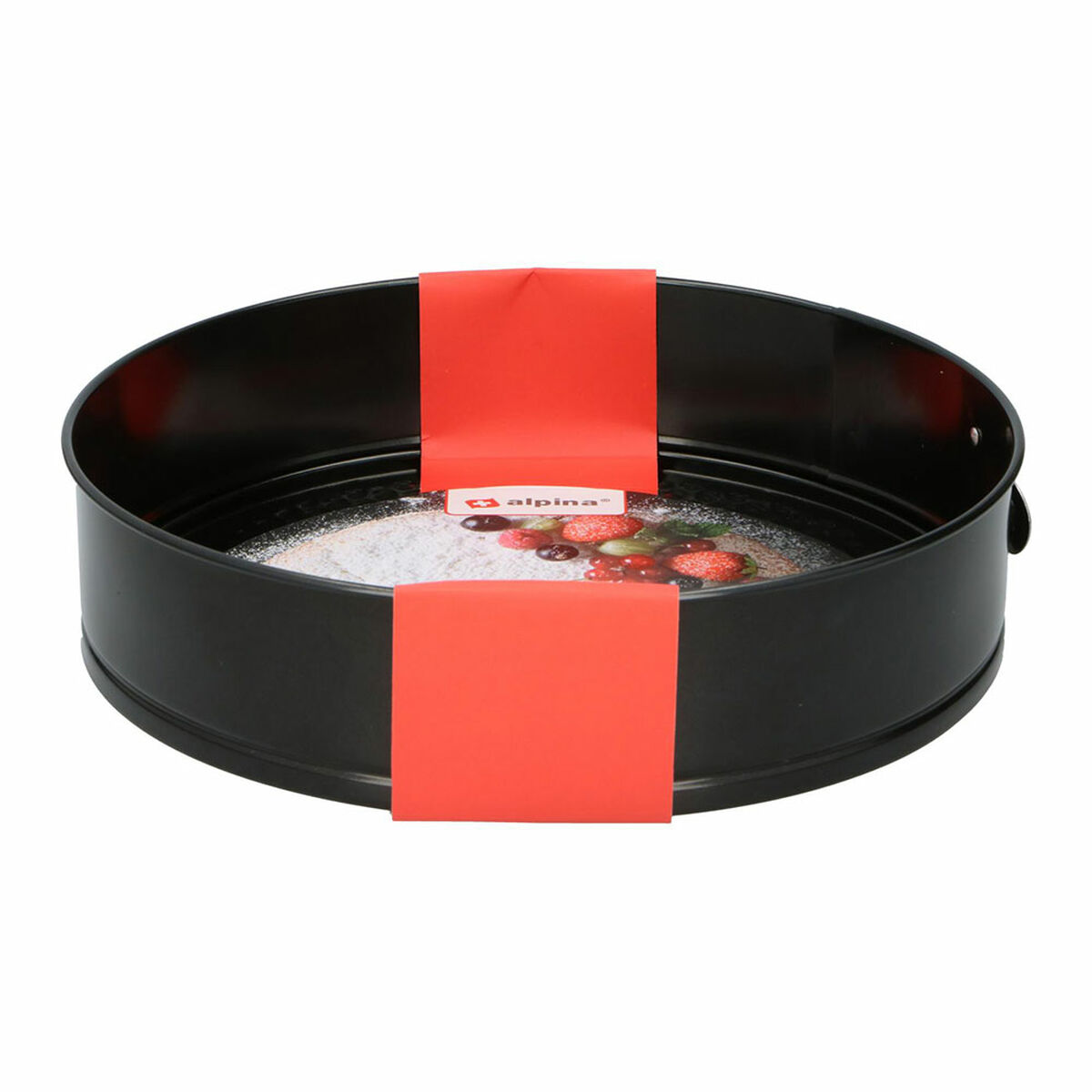 Un moule à gâteau rond noir avec une bande rouge. Il y a un gâteau à l'intérieur avec des baies rouges dessus.