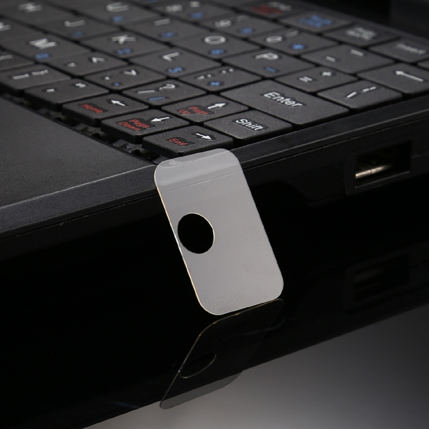 Eine silberne Laptop-Tastatur mit einem eingesetzten silbernen Kartenleser. Schwarze Oberfläche.