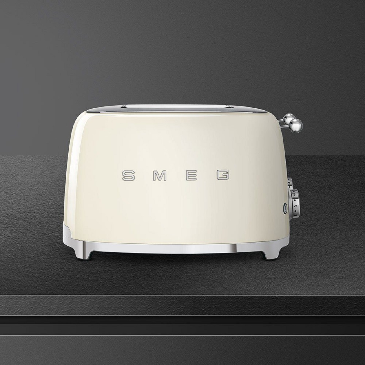 Cremefarbener SMEG Toaster auf schwarzer Oberfläche. Chromakzente, Vorderansicht.