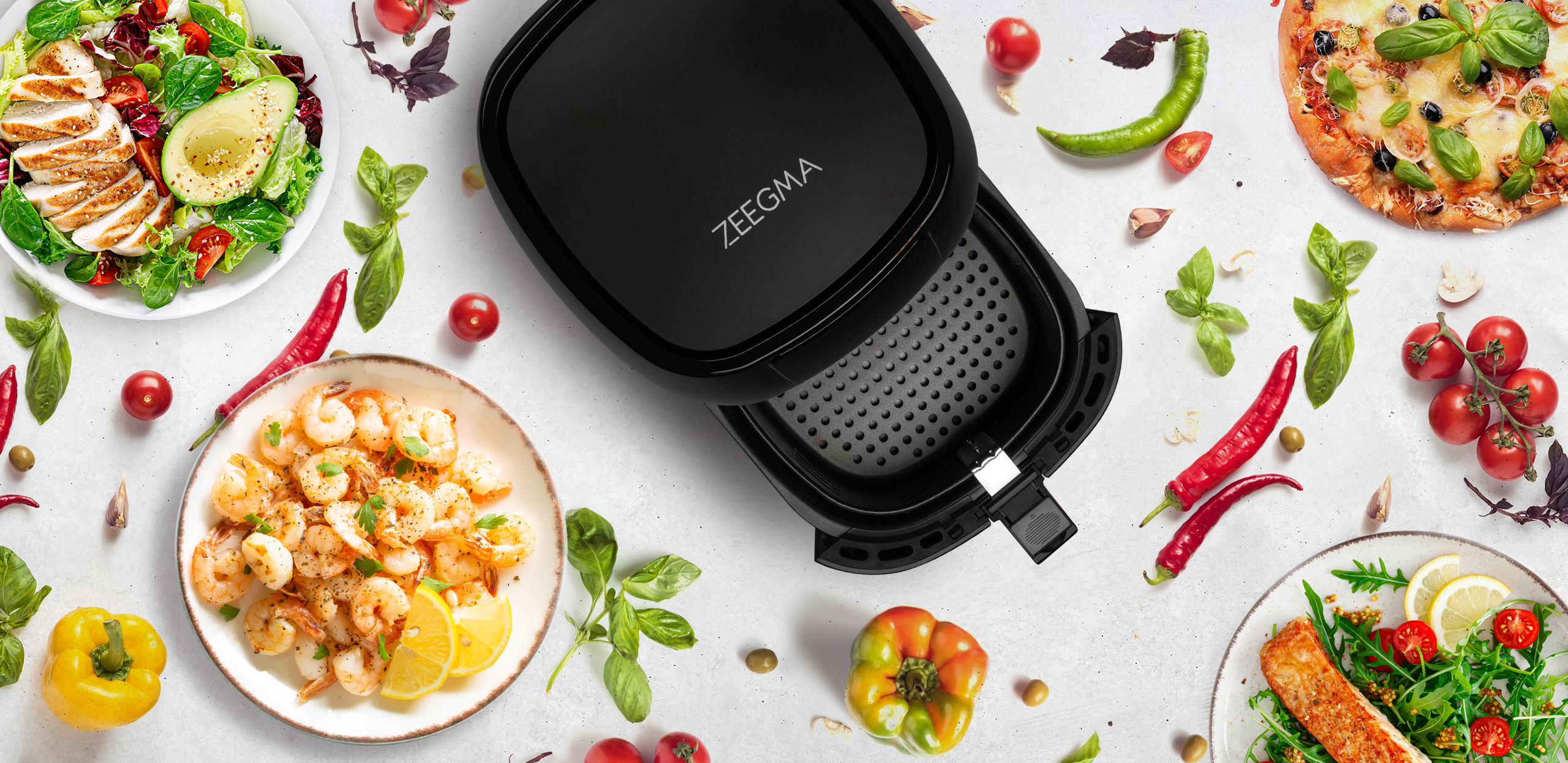 Czarna frytkownica powietrzna z otwartą pokrywą. Jedzenie: pizza, sałatka, krewetki. Warzywa i zioła dookoła.